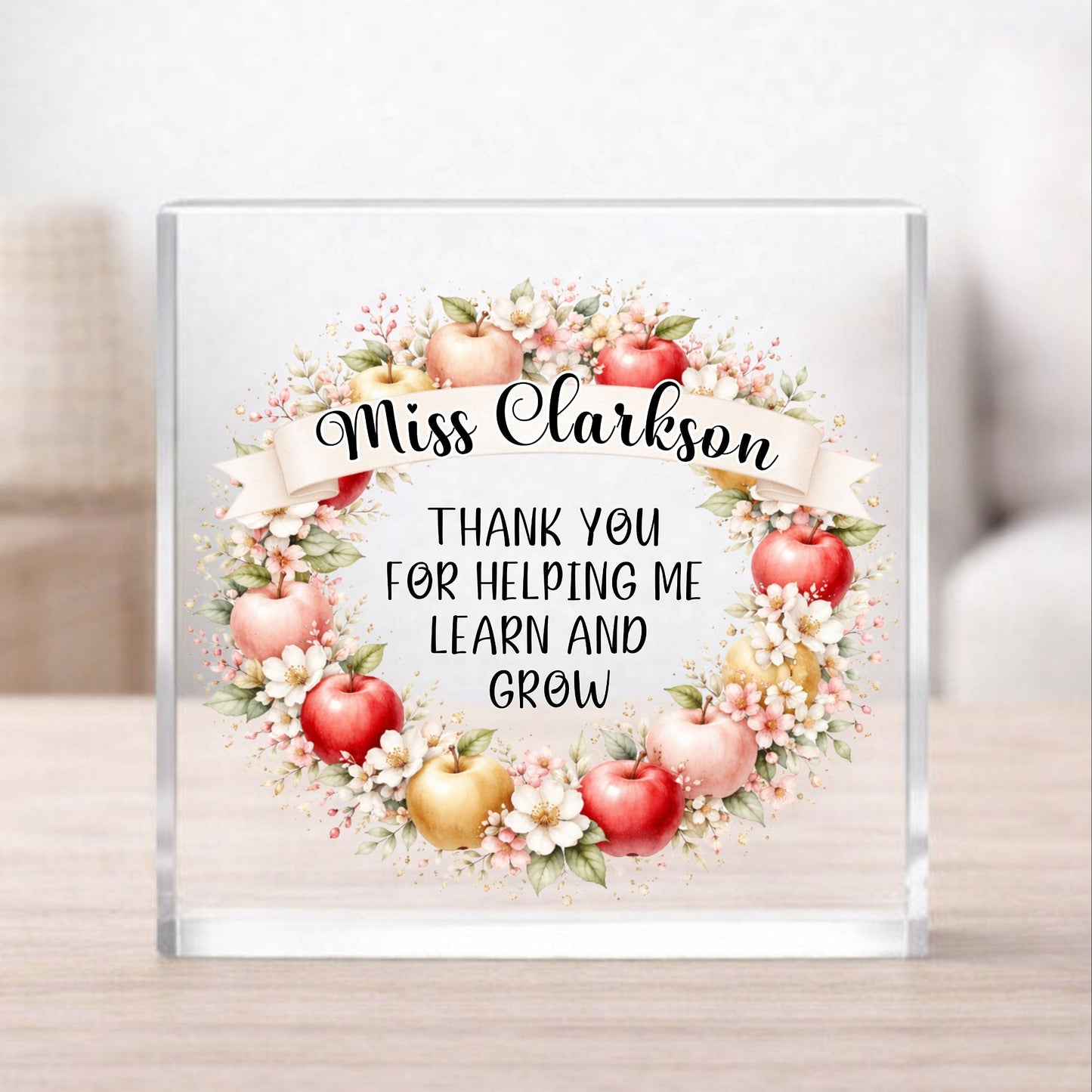 Glass block with floral design and text 'Miss Clarkson Thank you for helping me learn and grow' on a wooden surface.