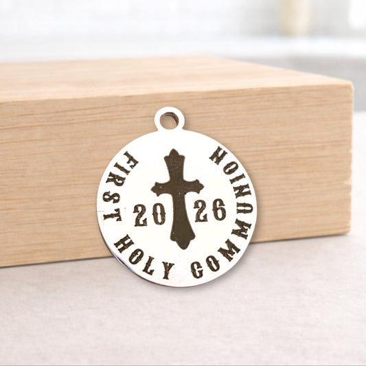 Round metal pendant with cross and text on a wooden block