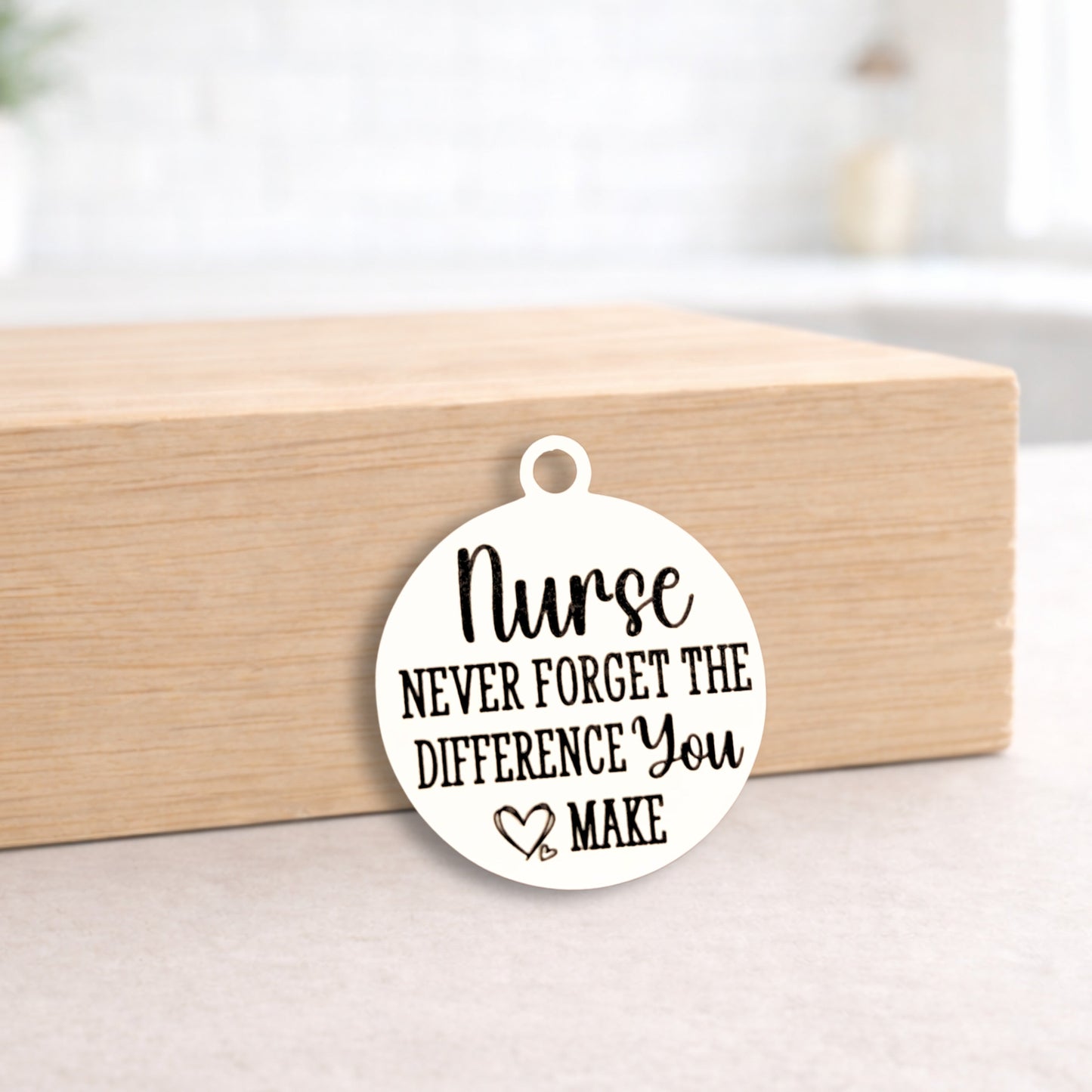 Round white pendant with 'Nurse Never Forget the Difference You Make' text on a wooden block.