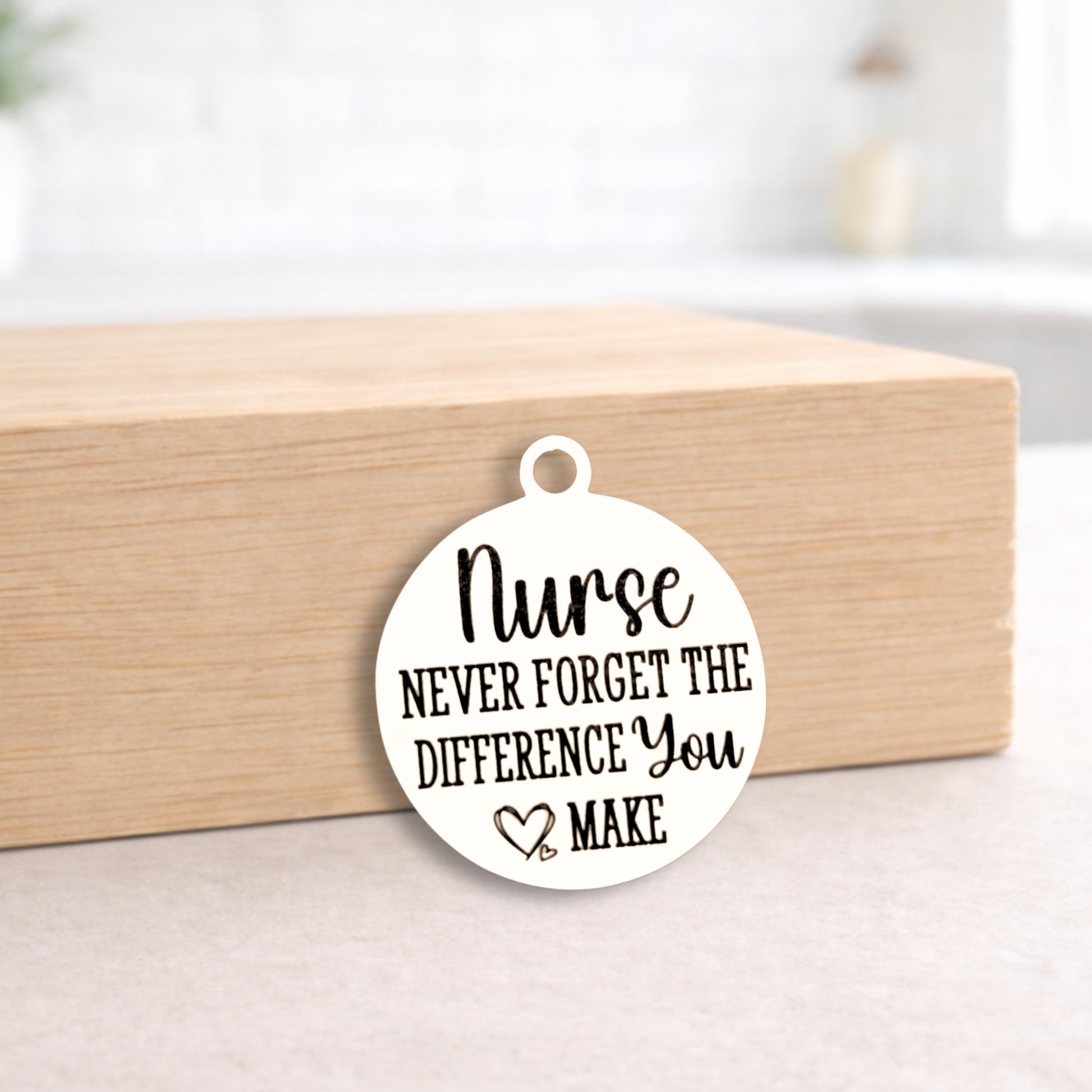 Round white pendant with 'Nurse Never Forget the Difference You Make' text on a wooden block.