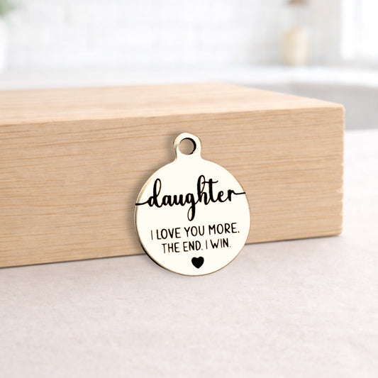 Round metal pendant with engraved text on a wooden block