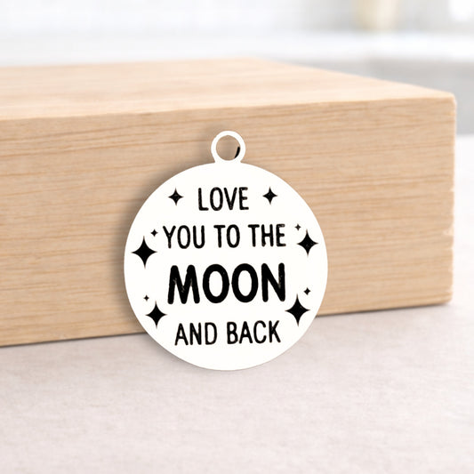 Circular pendant with 'Love you to the moon and back' text on a wooden block.