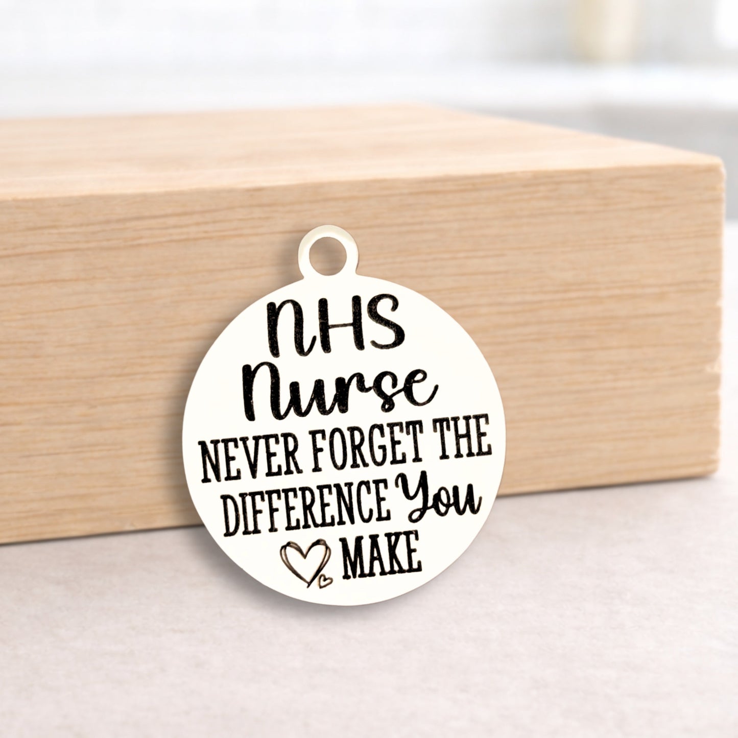 Round pendant with 'NHS Nurse Never Forget the Difference You Make' text on a wooden block.