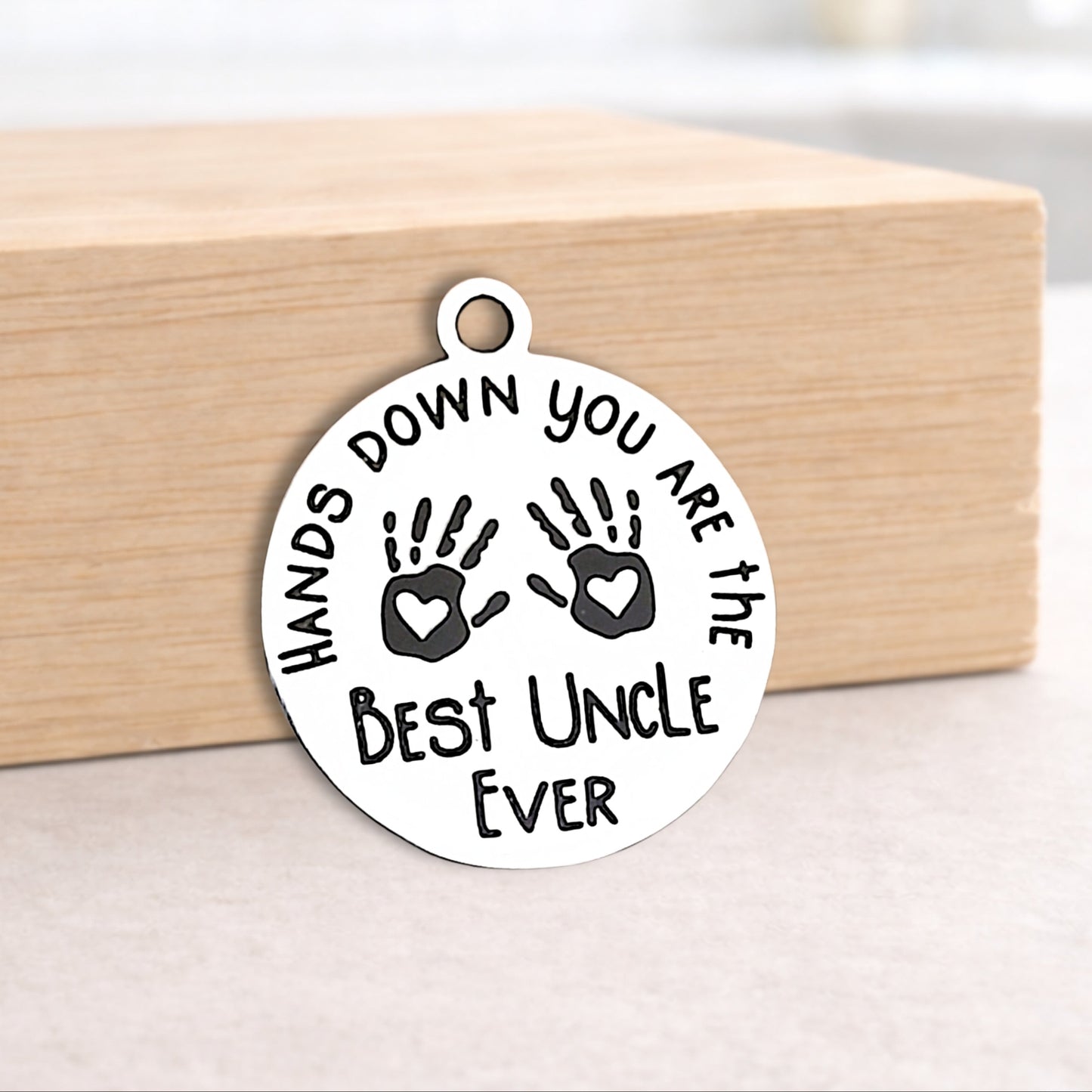Circular pendant with engraved text and handprints on a wooden block.
