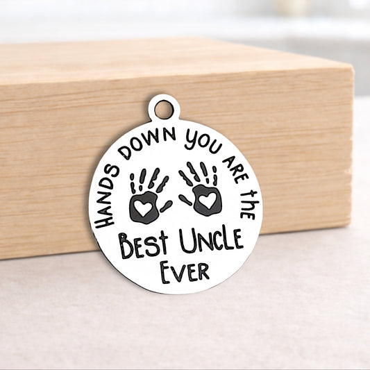 Circular pendant with engraved text and handprints on a wooden block.