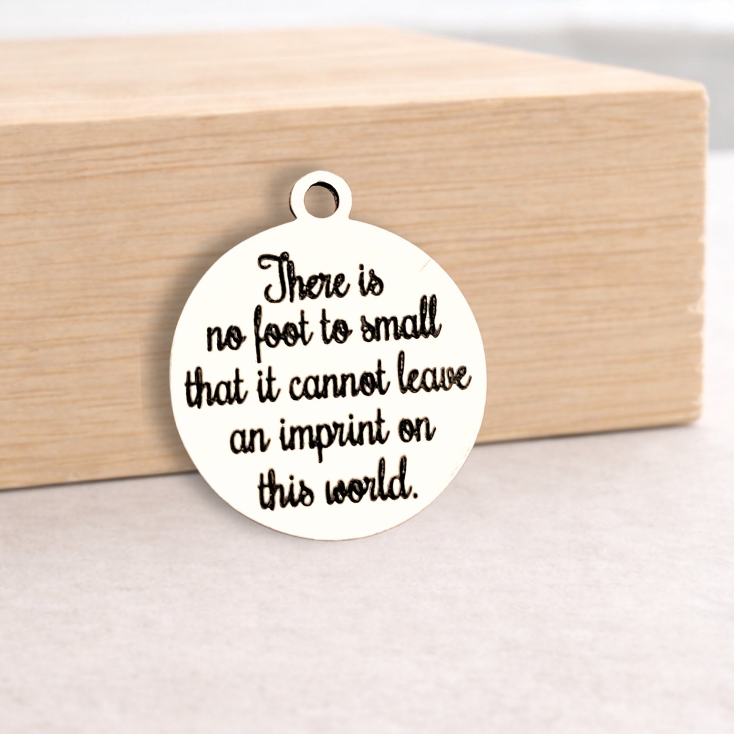 Round white pendant with black text on a wooden block