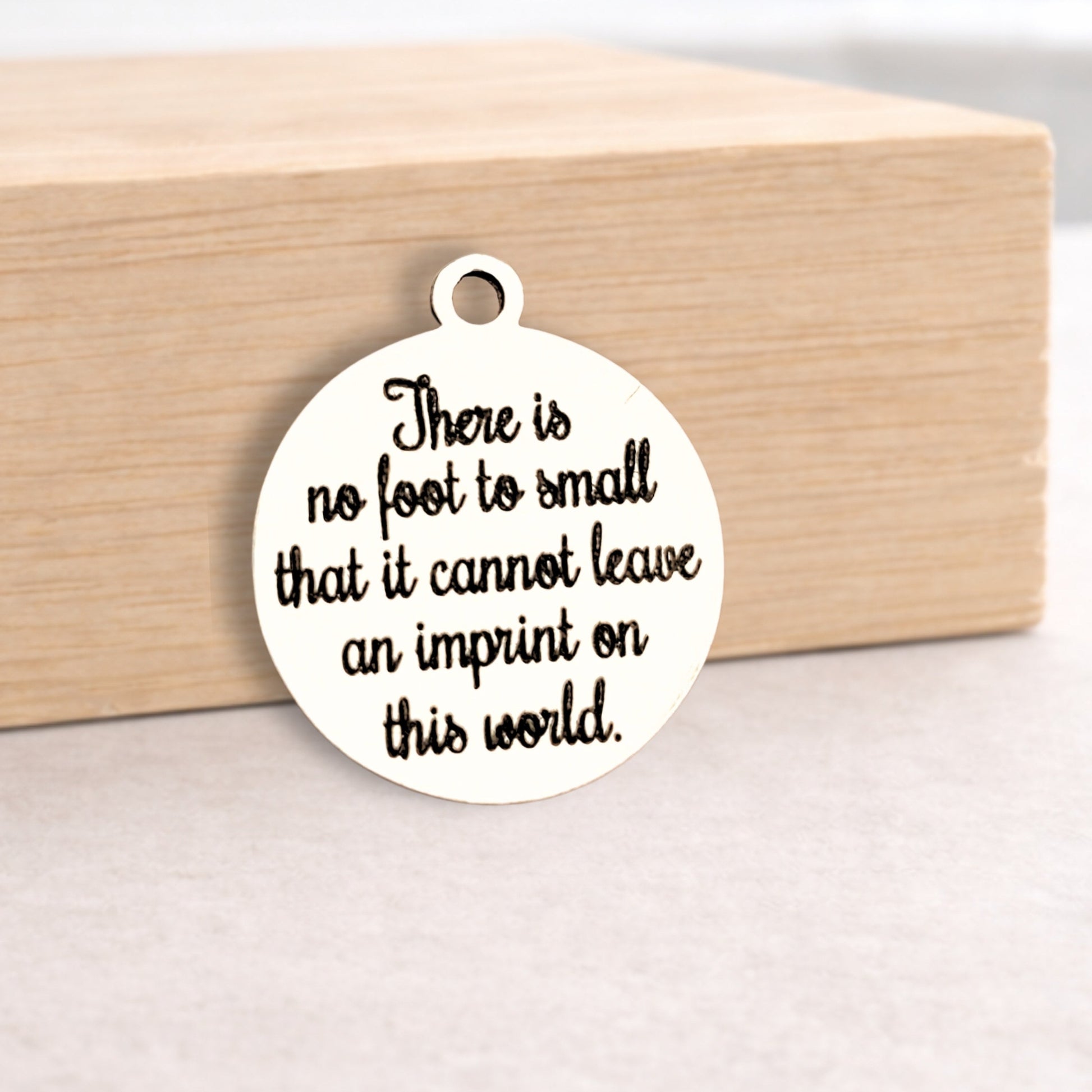 Round white pendant with black text on a wooden block