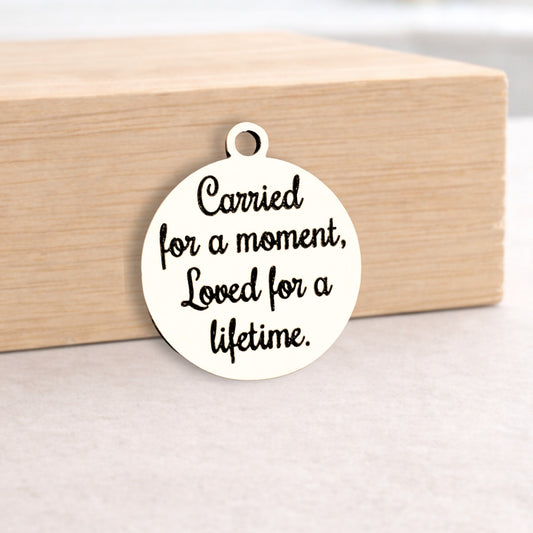 Round metal pendant with engraved text on a wooden block