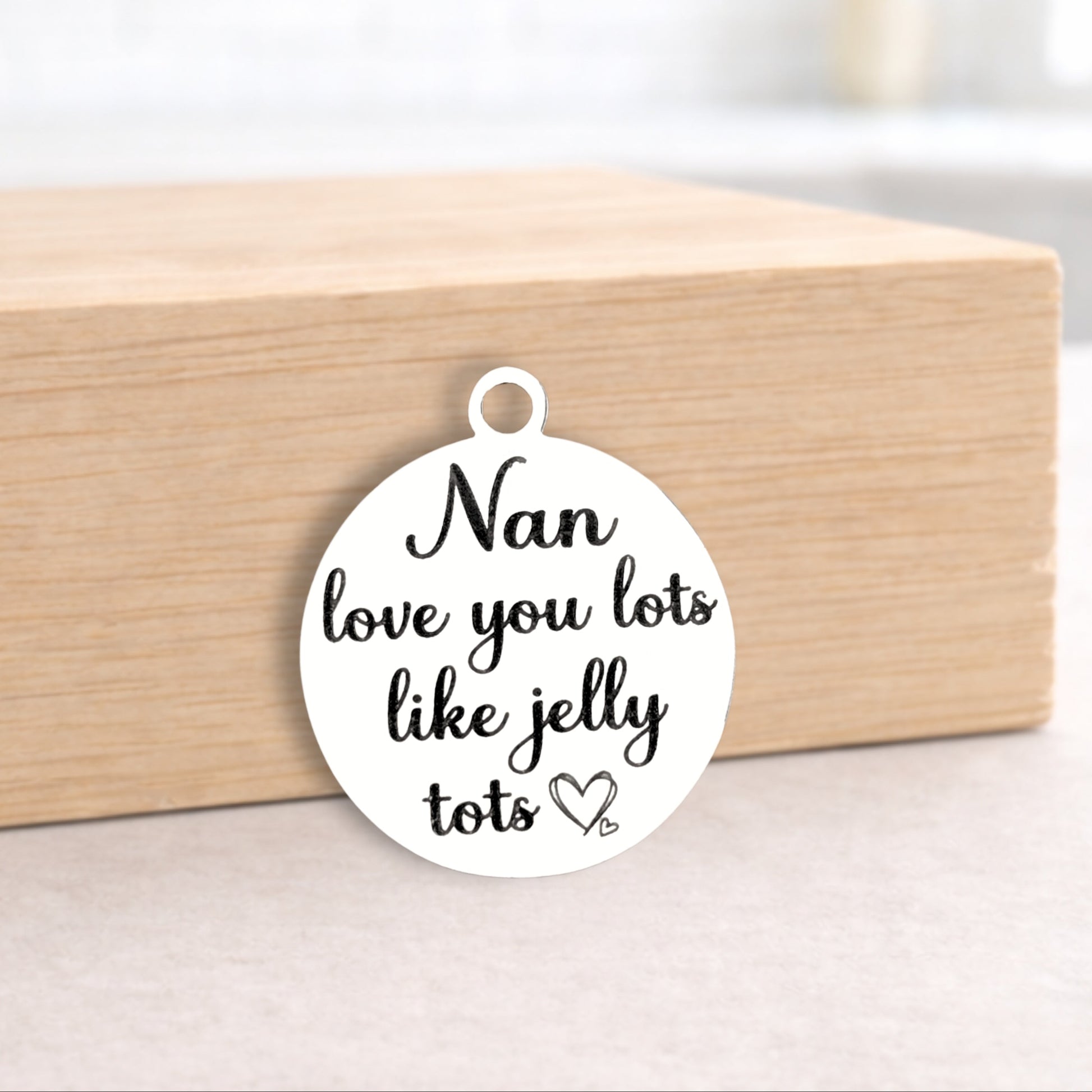 Round white pendant with 'Nan love you lots like jelly tots' text on a wooden block.