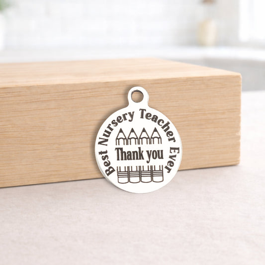 Silver pendant with 'Best Nursery Teacher Ever Thank you' text on a wooden block.