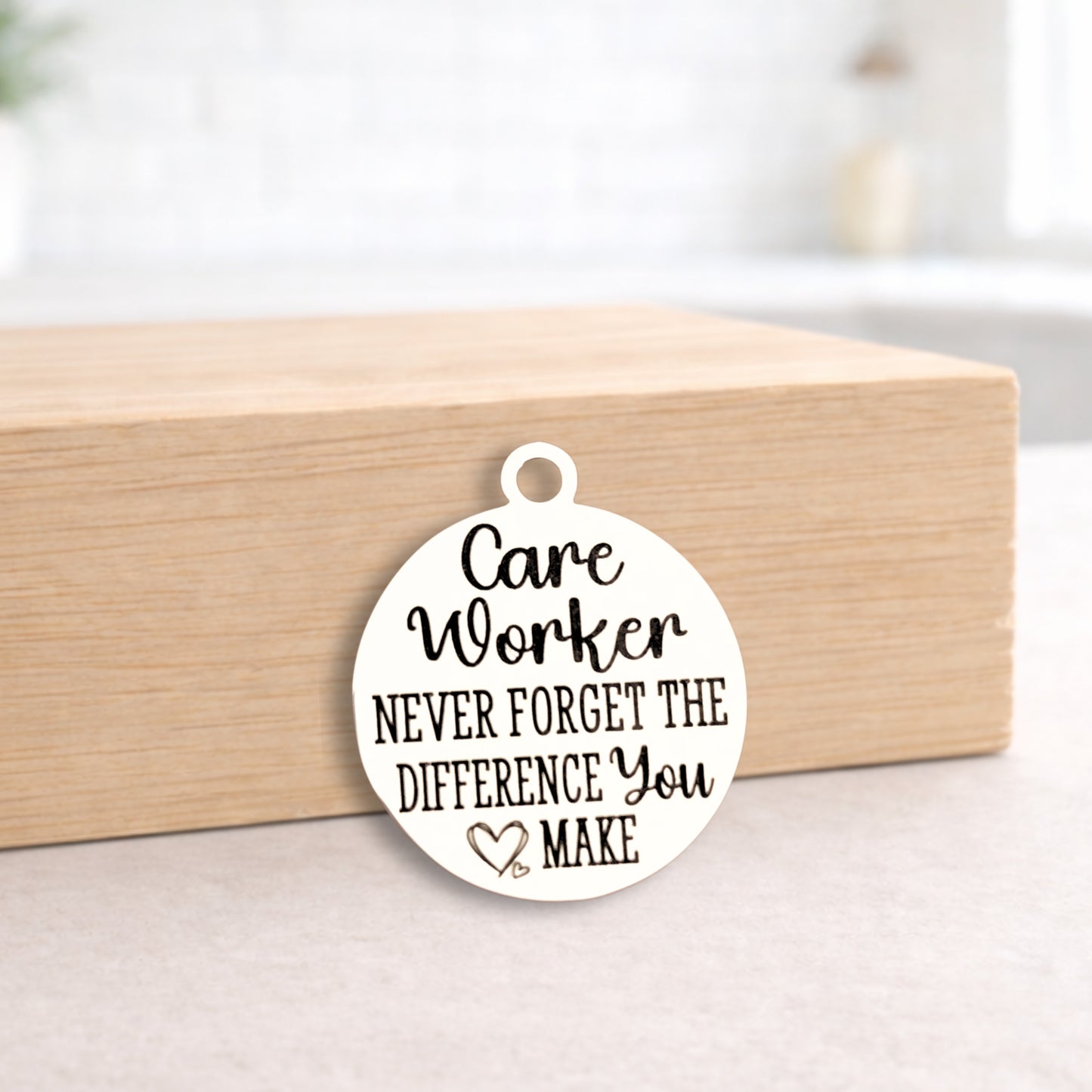 Round pendant with 'Care Worker Never Forget the Difference You Make' text on a wooden block.