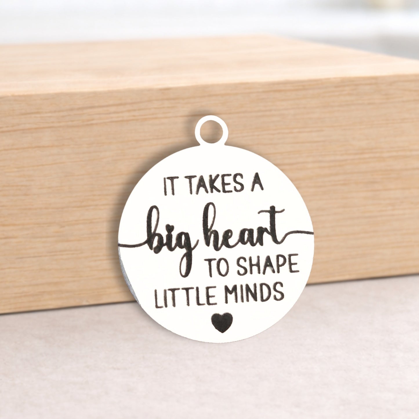 Round pendant with engraved text on a wooden block