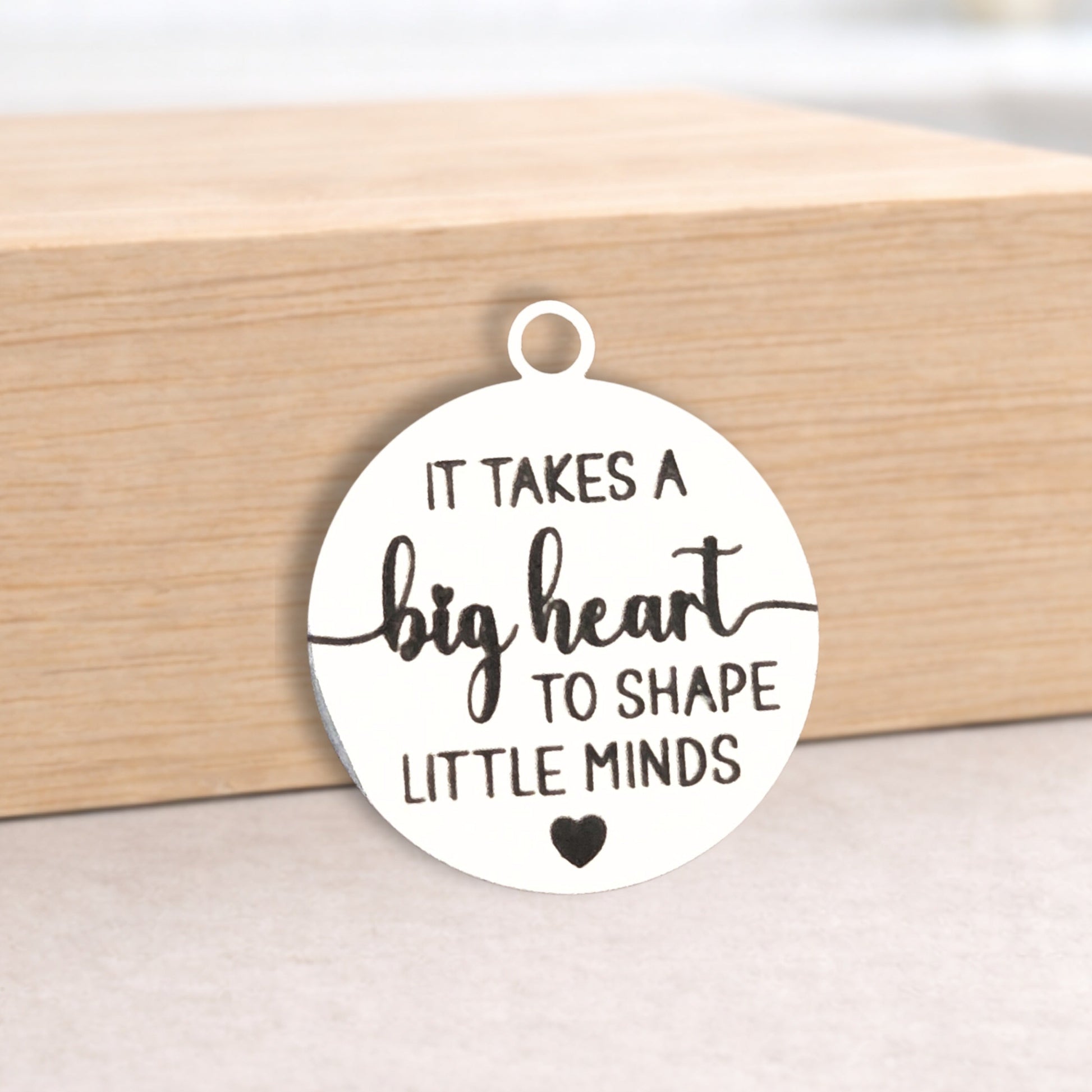 Round pendant with engraved text on a wooden block