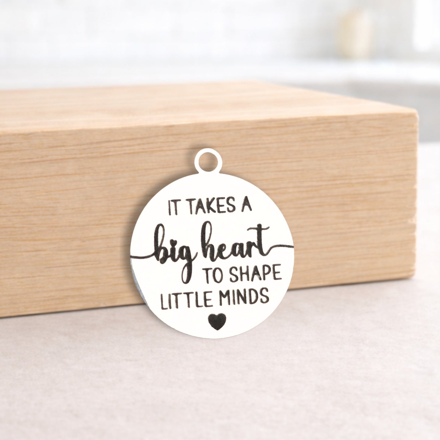 Round pendant with engraved text on a wooden block