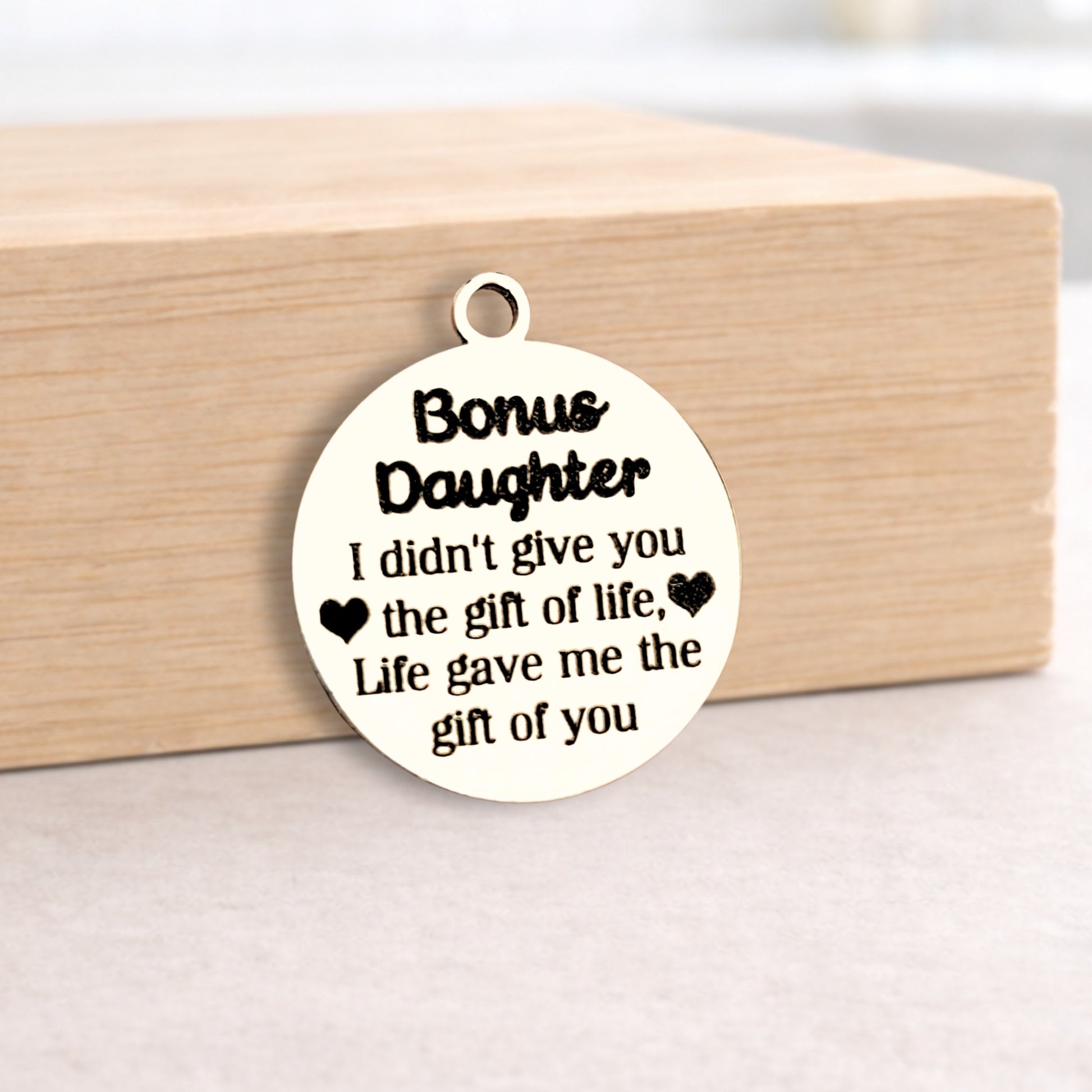 Silver pendant with engraved text on a wooden block