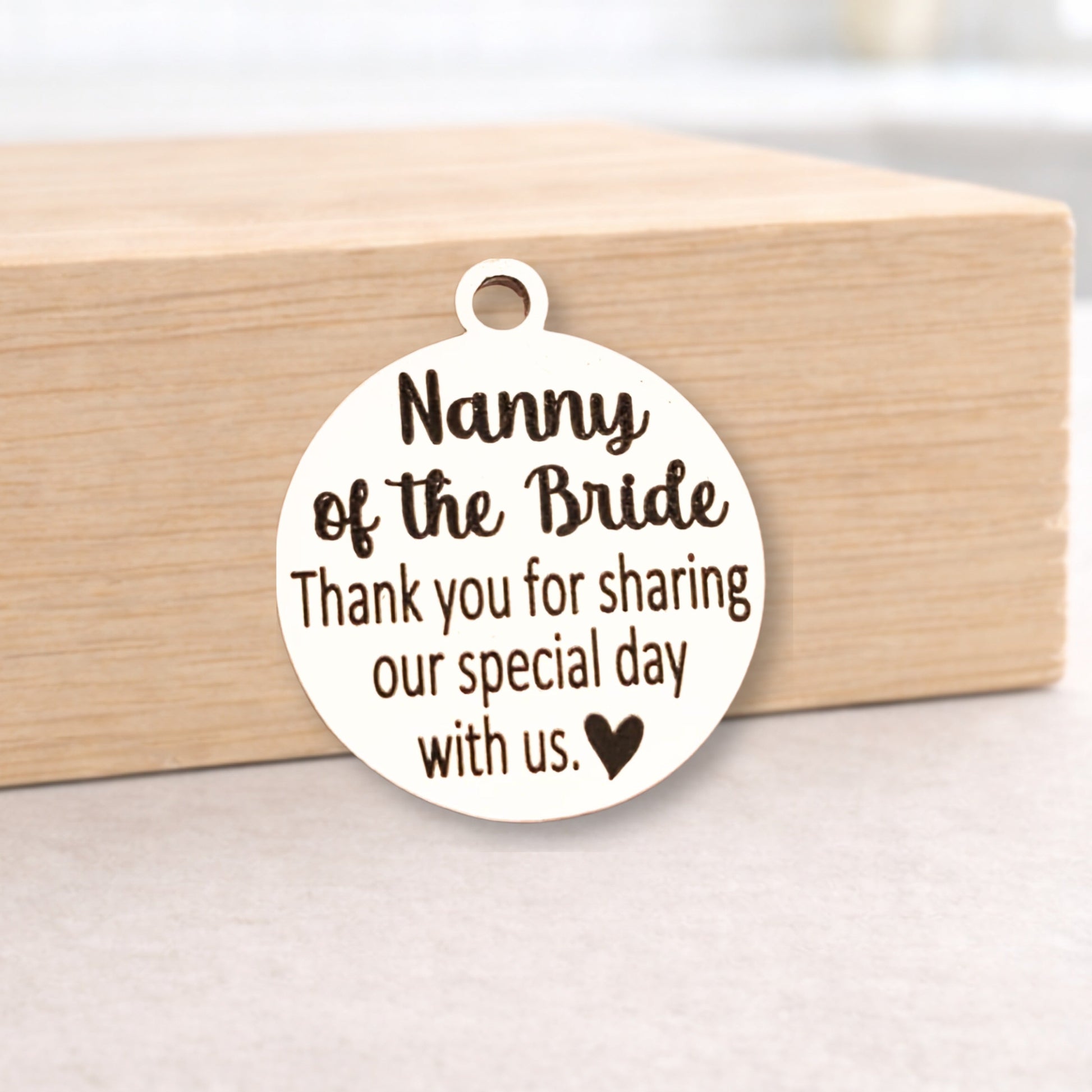 Round metal pendant with engraved text on a wooden block