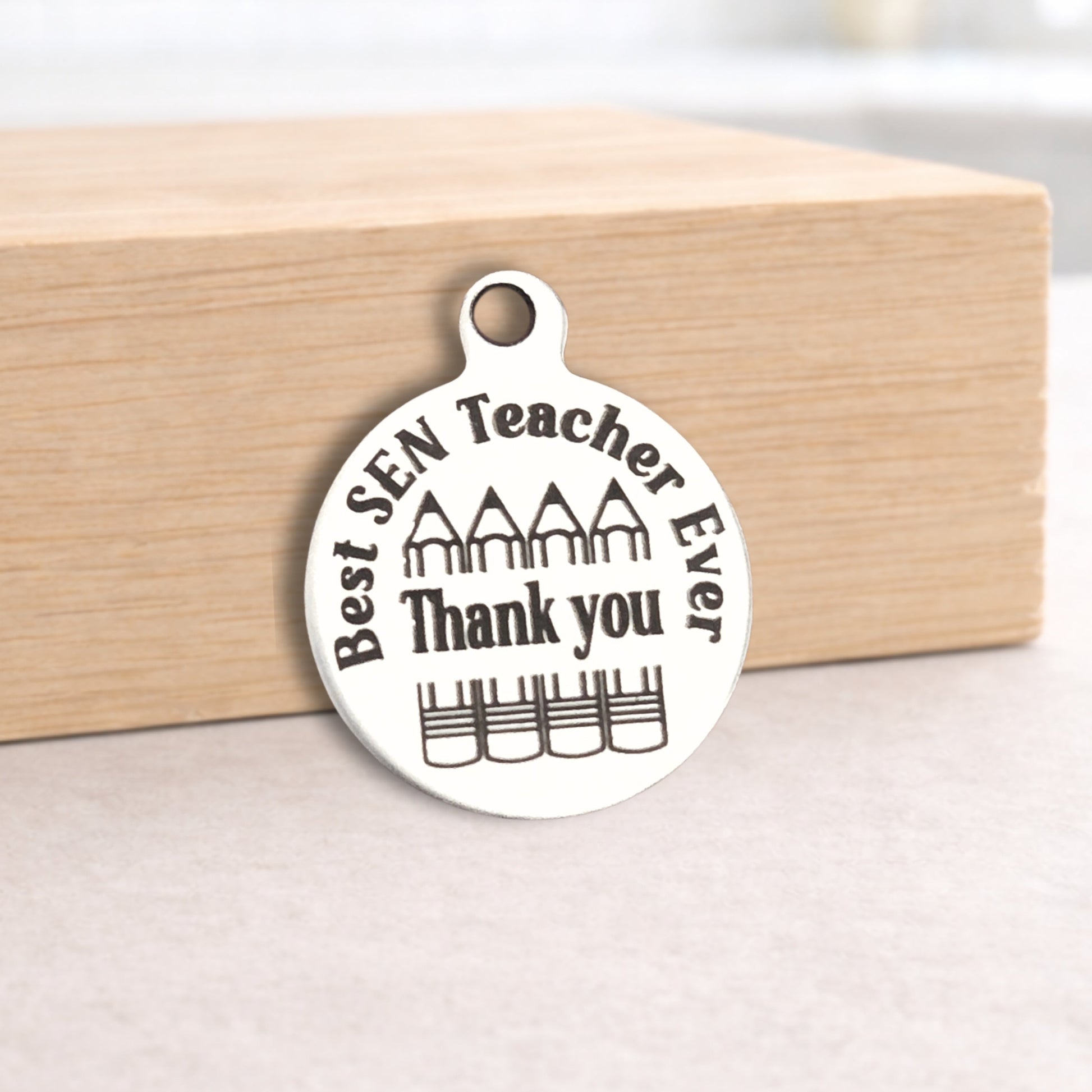 Silver pendant with 'Best SEN Teacher Ever Thank you' text on a wooden block.