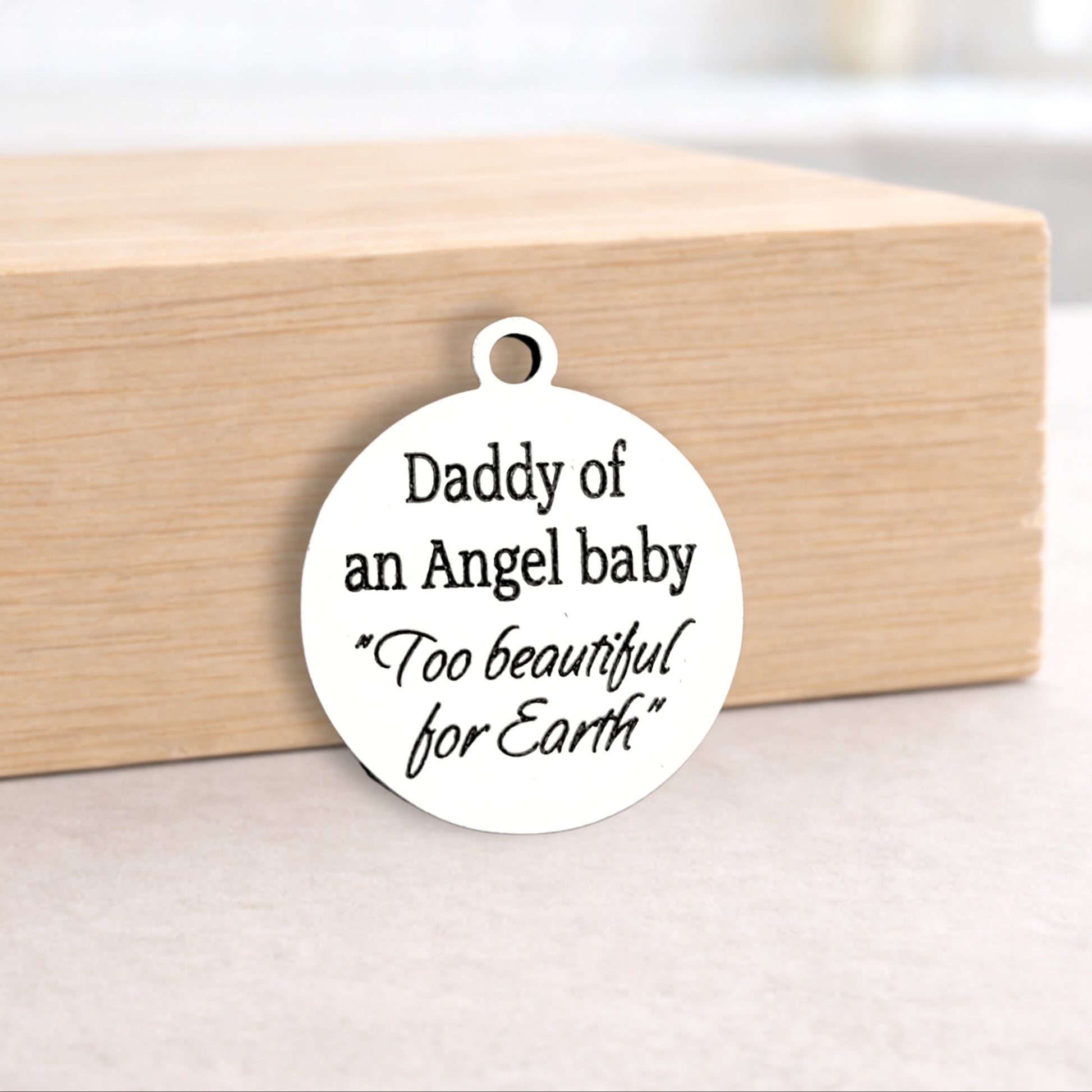 Round white pendant with engraved text on a wooden block
