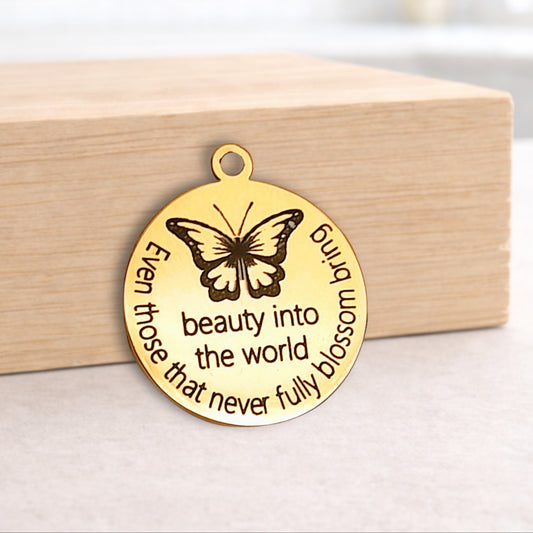 Gold butterfly pendant with engraved text on a wooden block