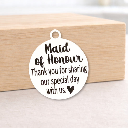 Round metal tag with 'Maid of Honour' text on a wooden block