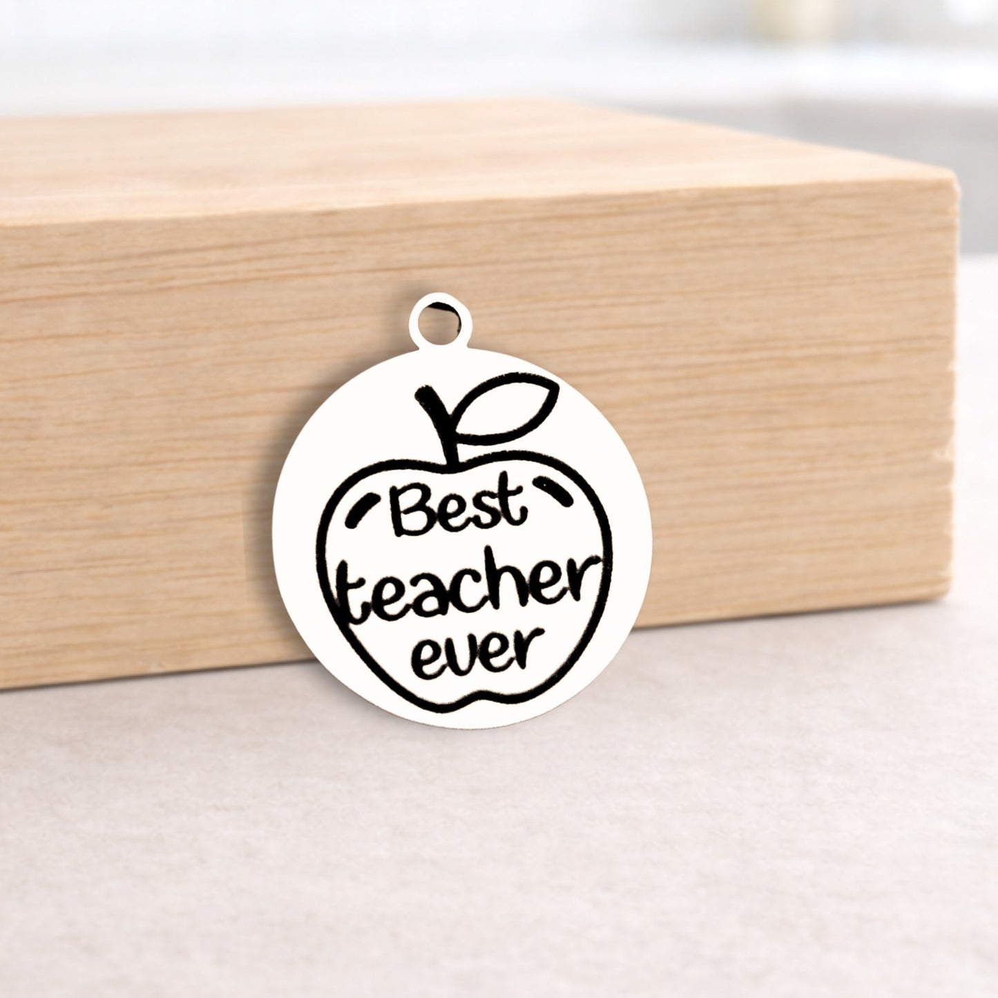 Metallic pendant with 'Best teacher ever' text on a wooden block