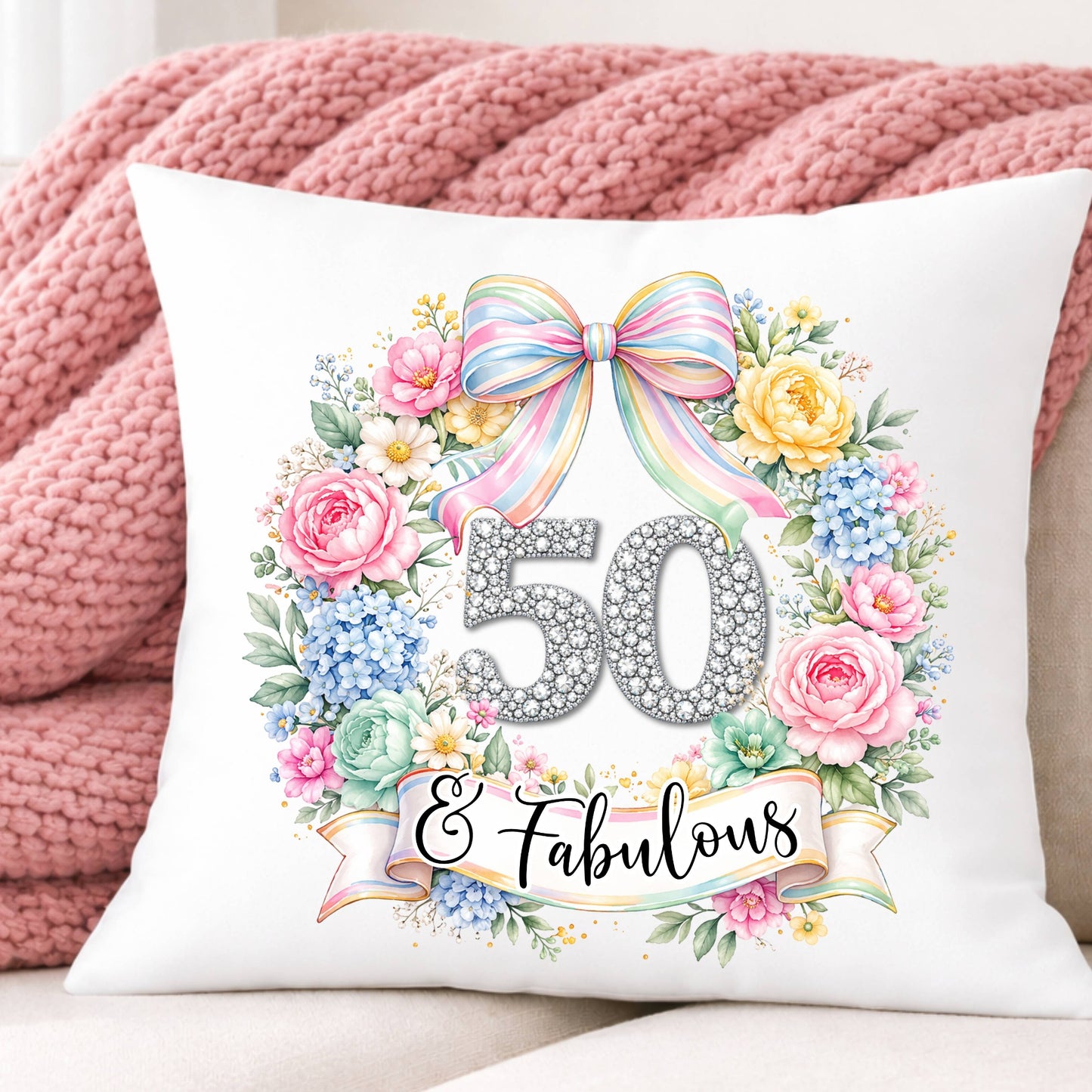 Decorative pillow with floral design and '50 & Fabulous' text on a pink blanket background