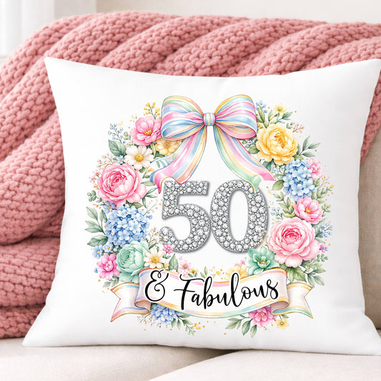 Decorative pillow with floral design and '50 & Fabulous' text on a pink blanket background