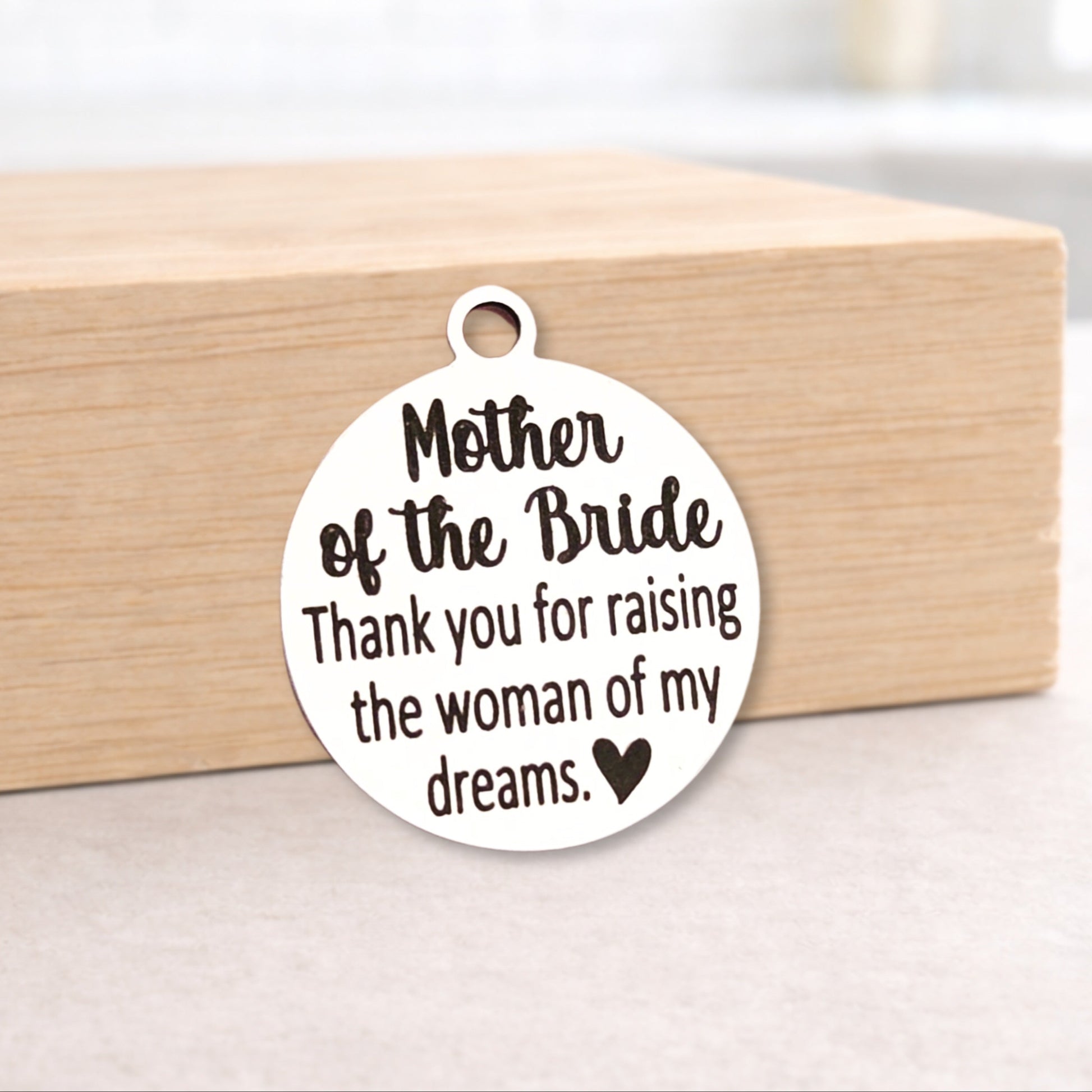 Round metal pendant with engraved text on a wooden block