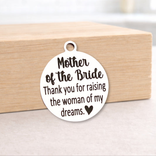 Round metal pendant with engraved text on a wooden block