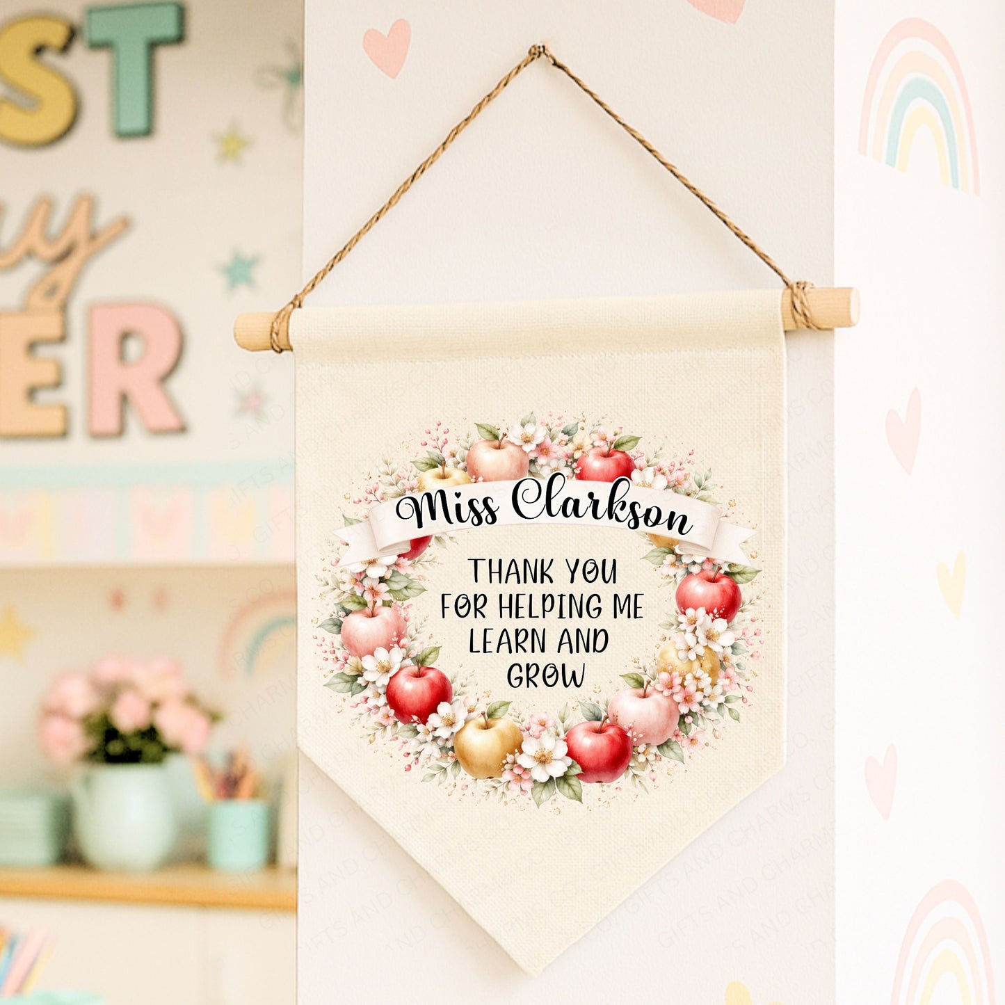 Decorative banner with floral Apple design and text, hanging against a colorful classroom background.