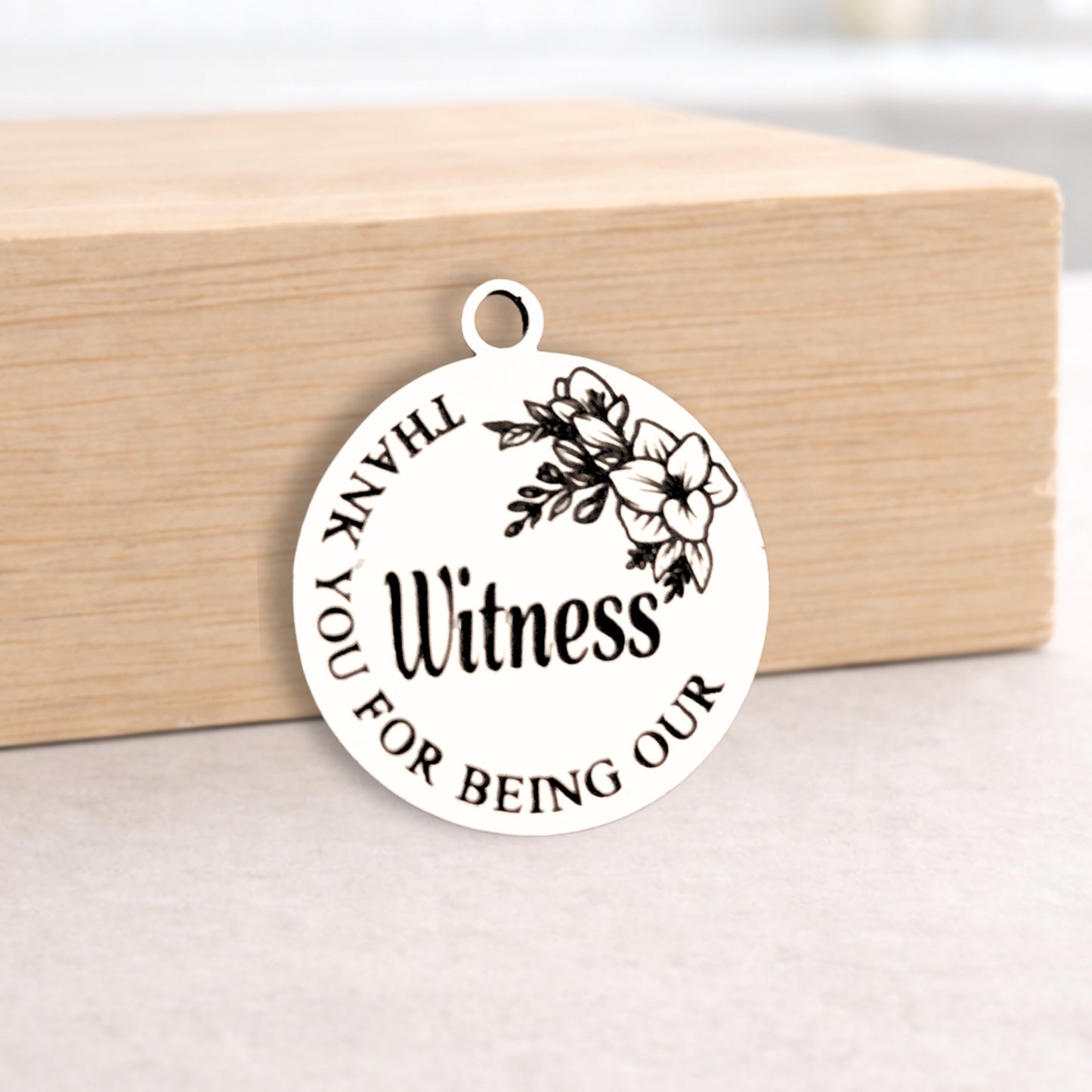 Round metal pendant with engraved text on a wooden block