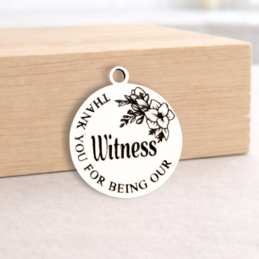 Round metal pendant with engraved text on a wooden block
