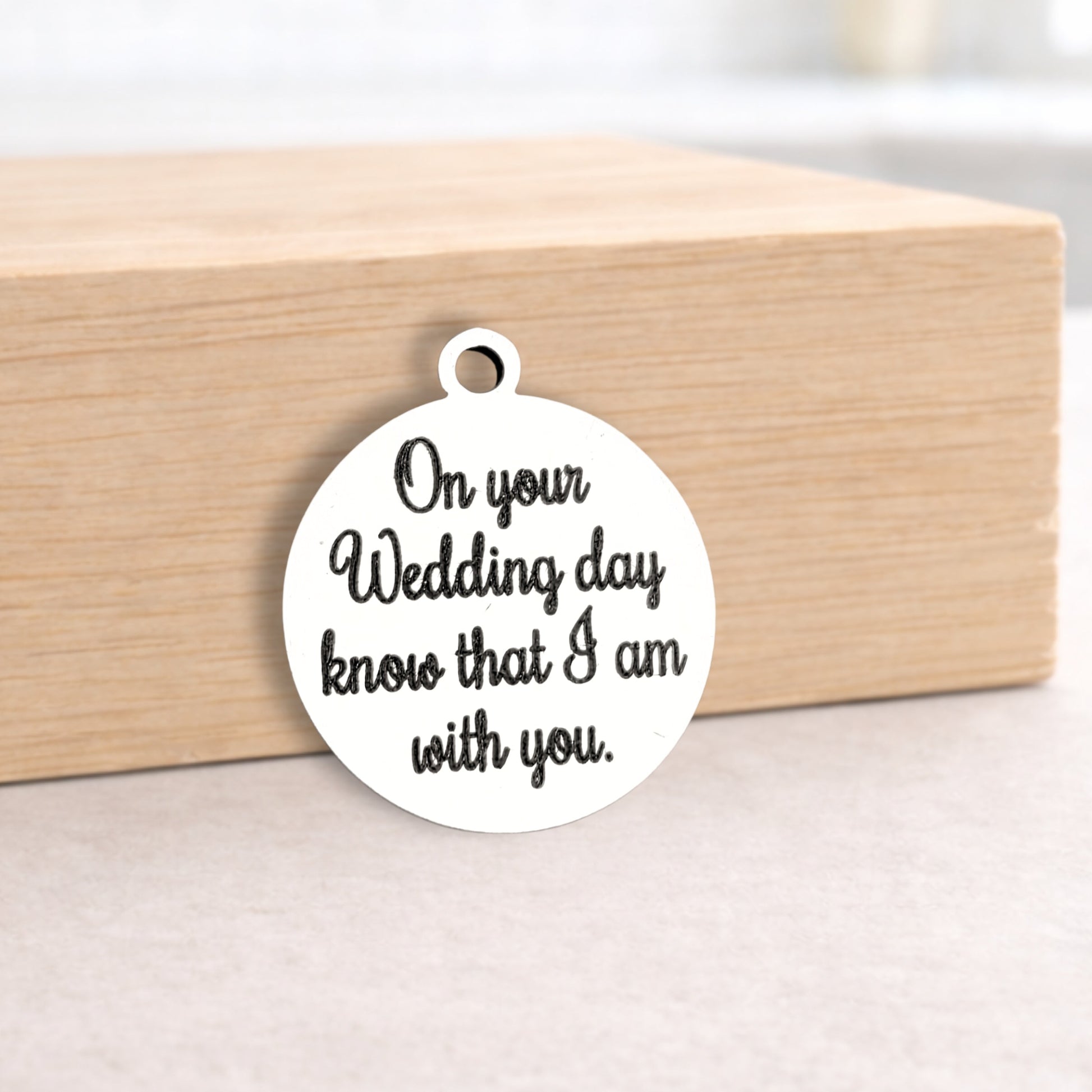 Round metal pendant with engraved text on a wooden block