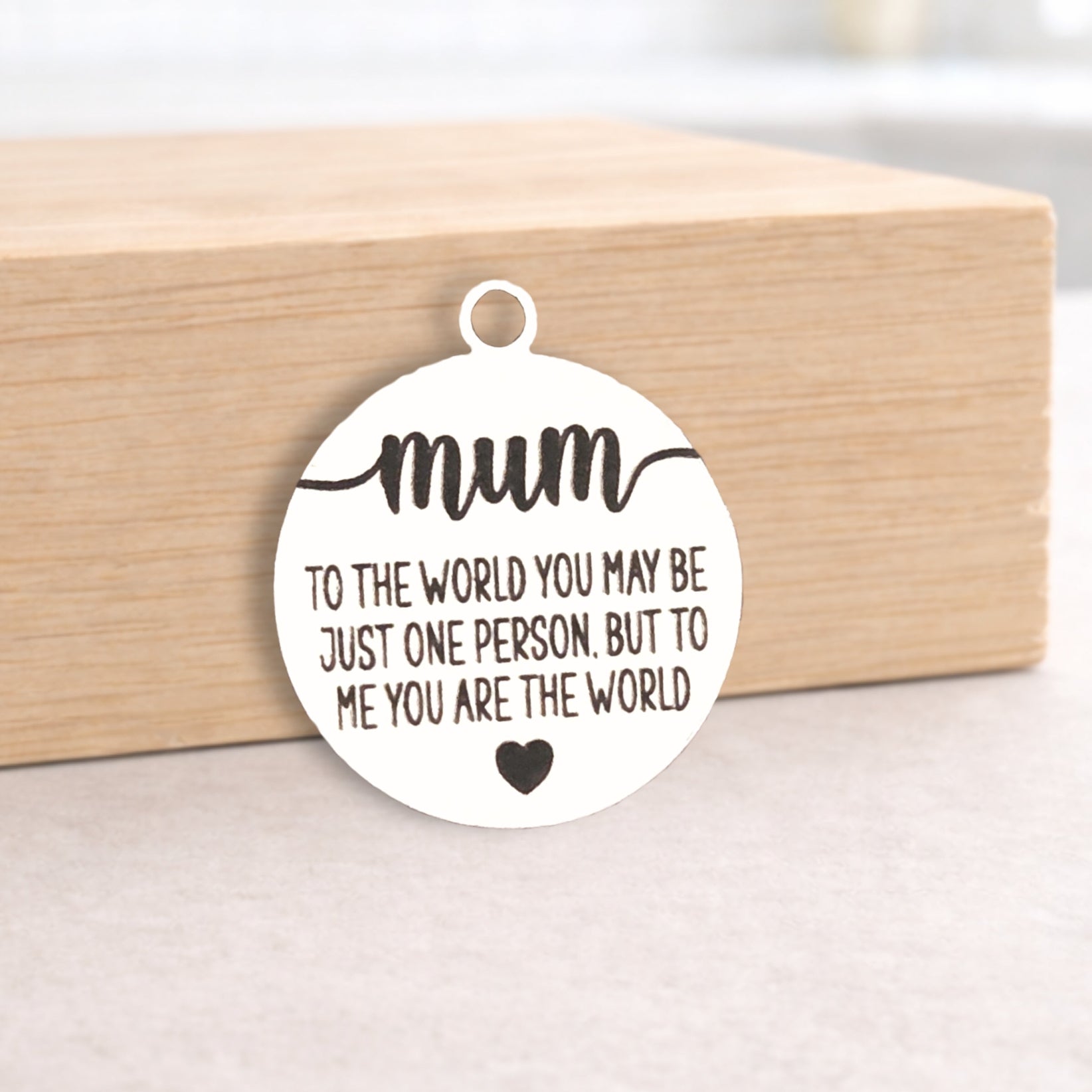 Circular pendant with engraved message on a wooden block