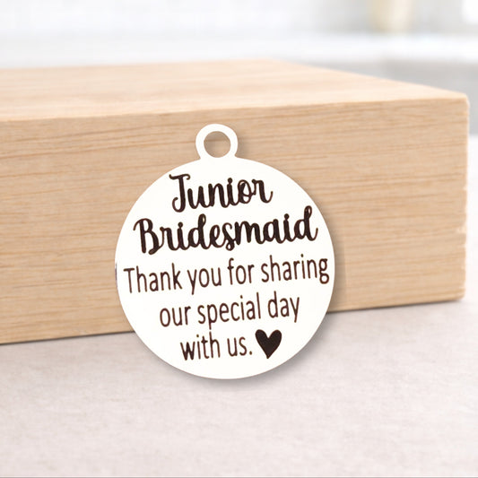 Round metal tag with 'Junior Bridesmaid' text on a wooden block