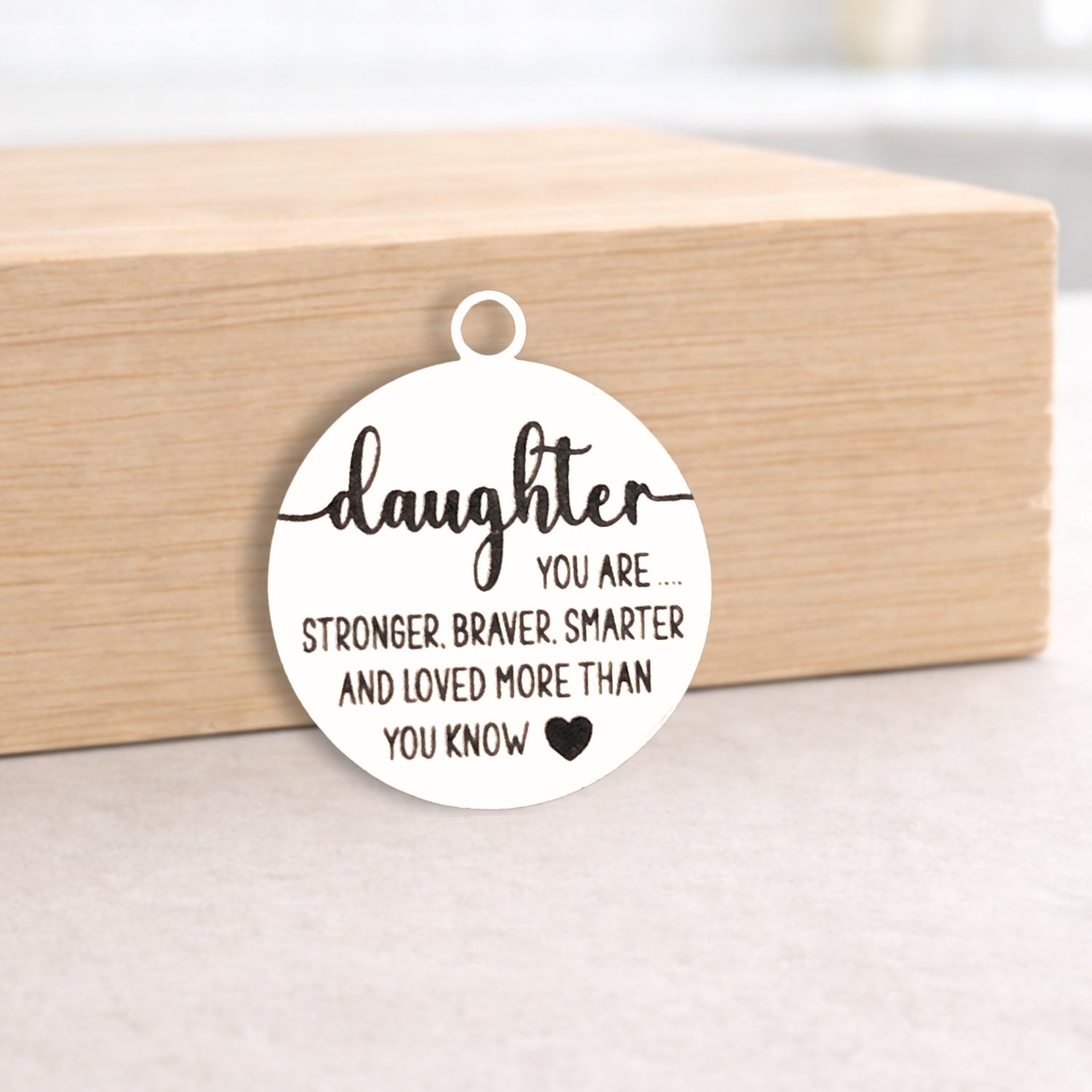 Circular pendant with engraved message on a wooden block