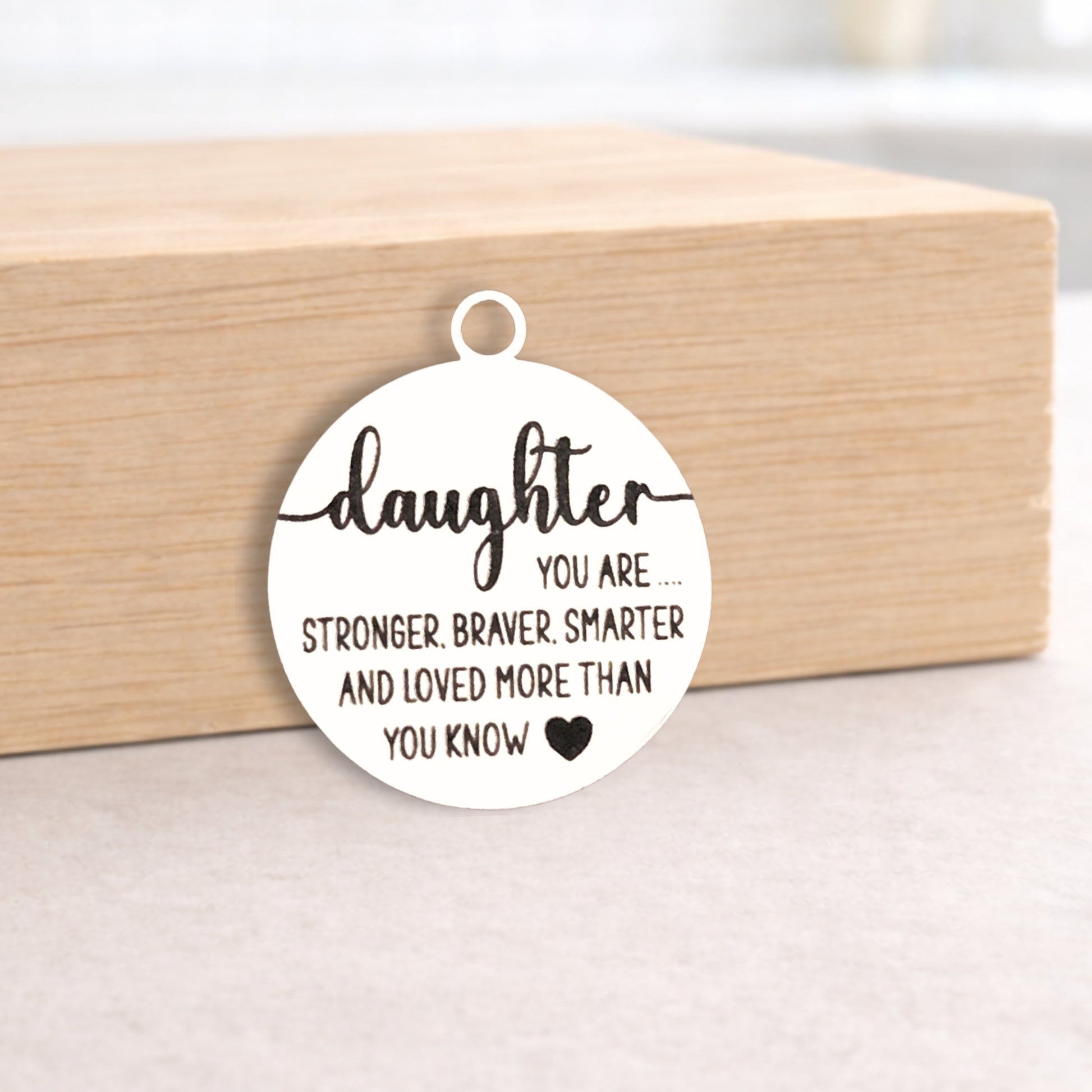 Circular pendant with engraved message on a wooden block