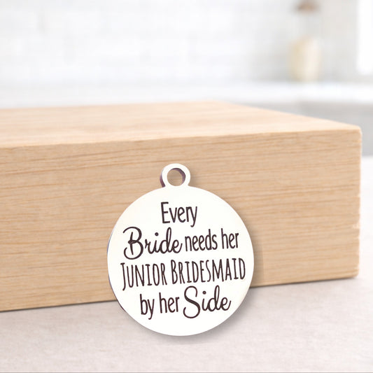 Round metal pendant with engraved text on a wooden box