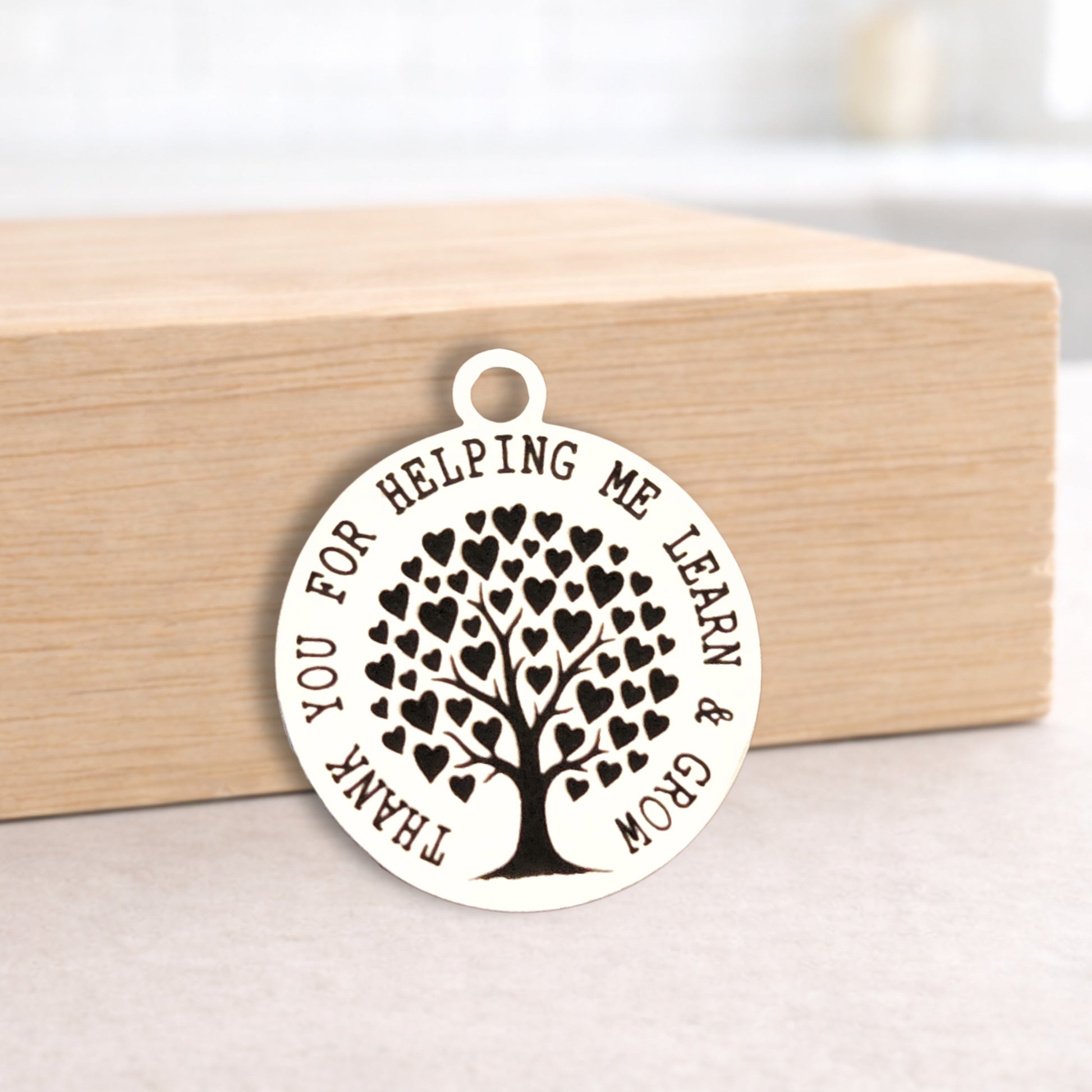 Round pendant with tree design and engraved text on a wooden block