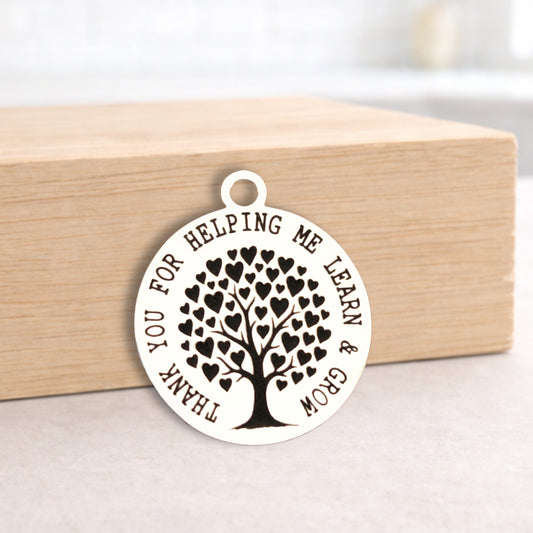 Round pendant with tree design and engraved text on a wooden block