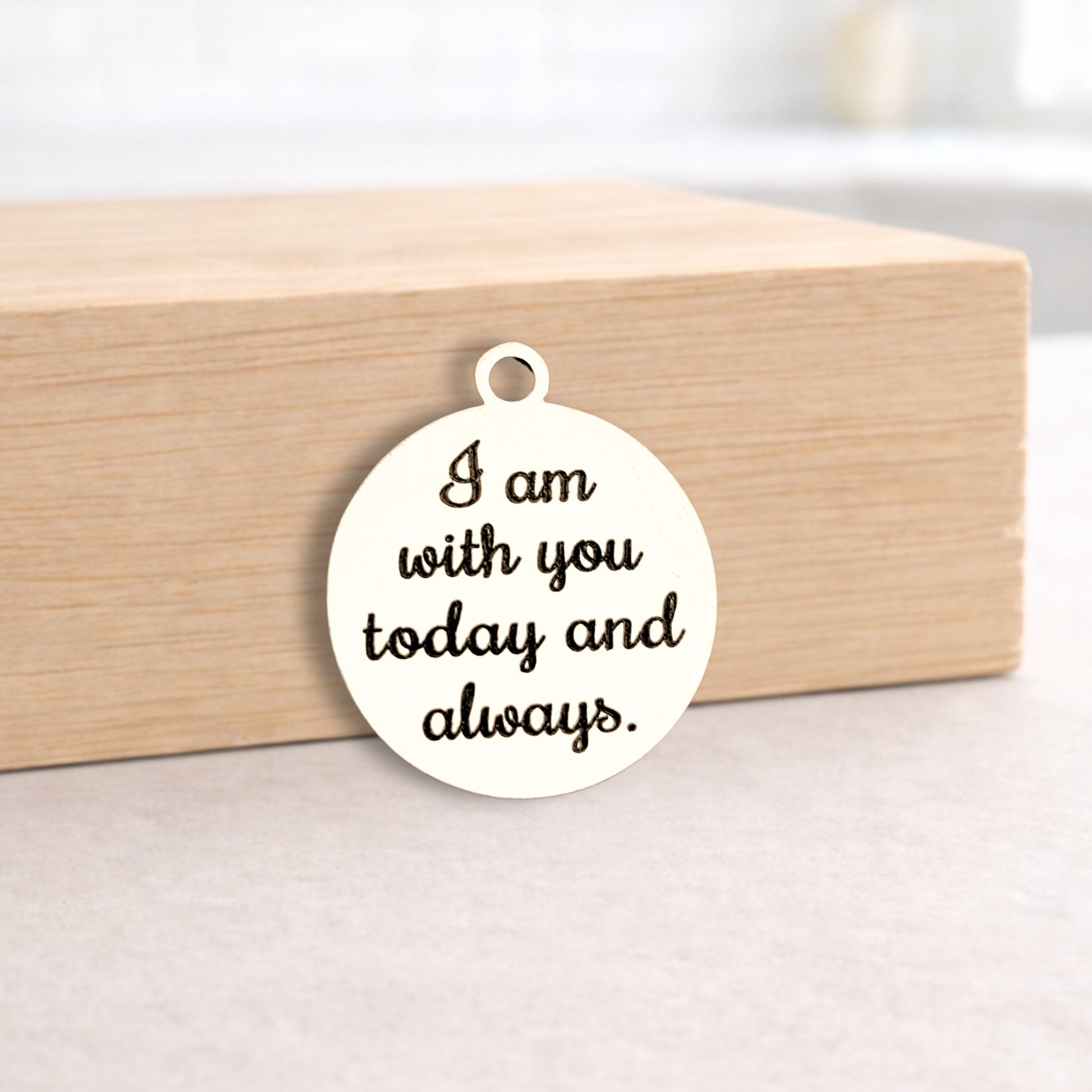 Round metal pendant with engraved text on a wooden block