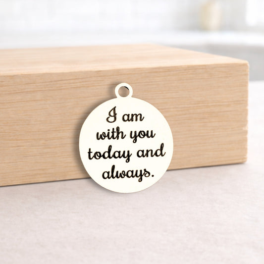 Round metal pendant with engraved text on a wooden block