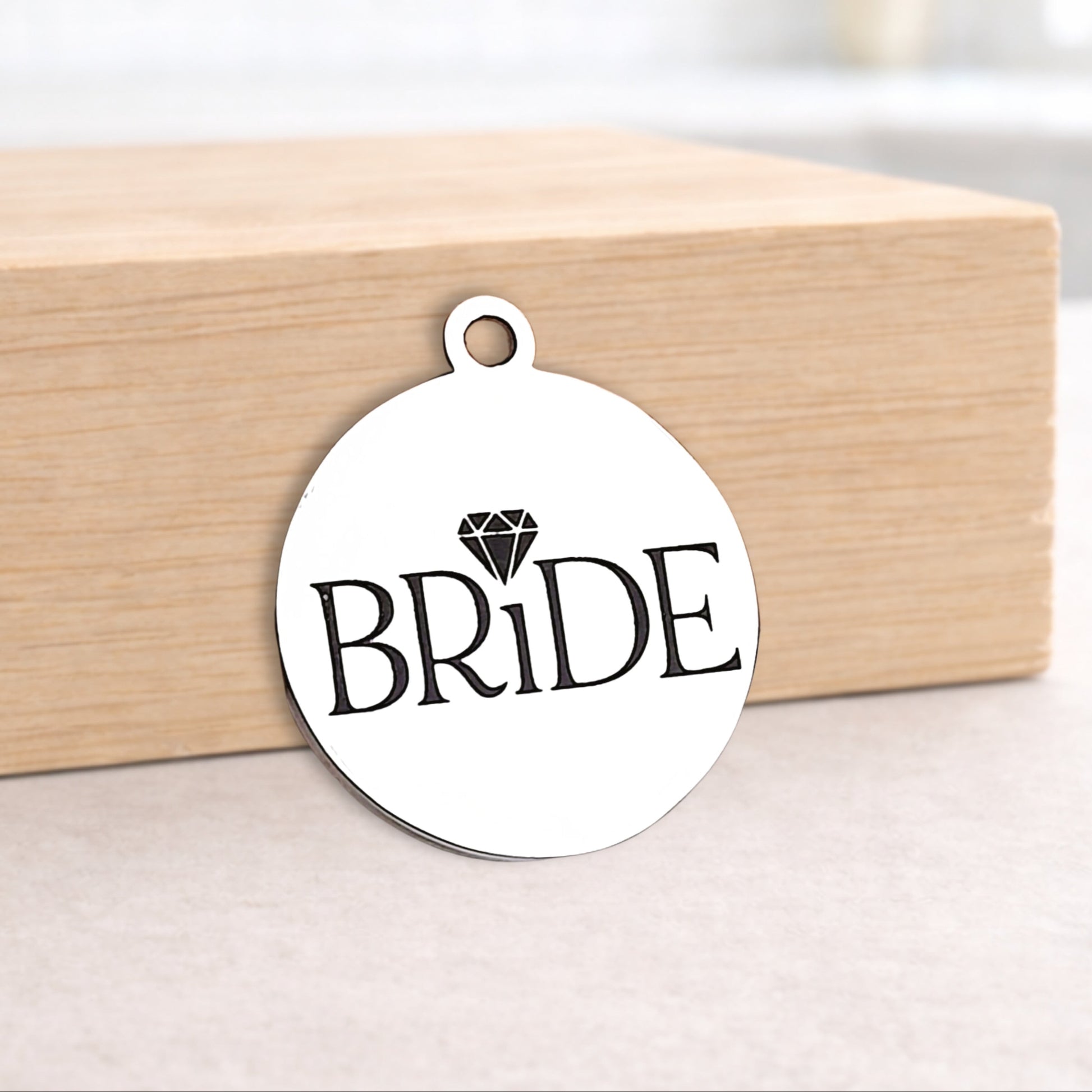 Metal pendant with 'BRIDE' text on a wooden block