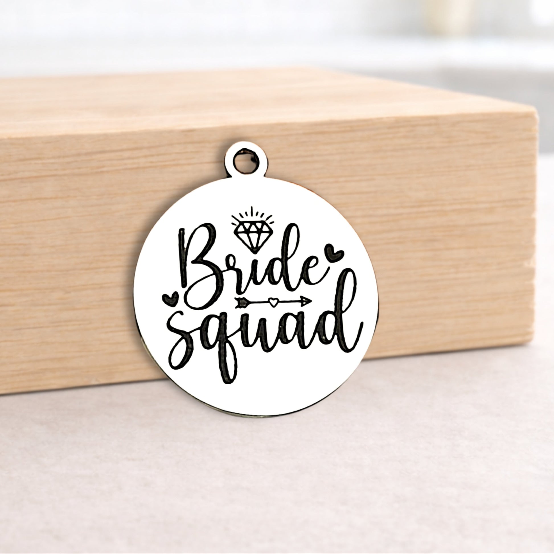 Circular pendant with 'Bride squad' text on a wooden block