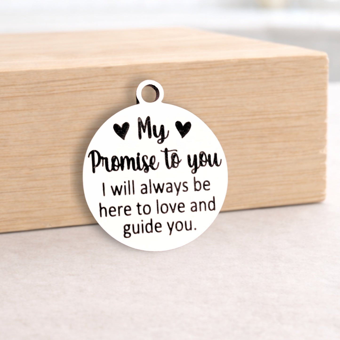 Round metal pendant with engraved message on a wooden block