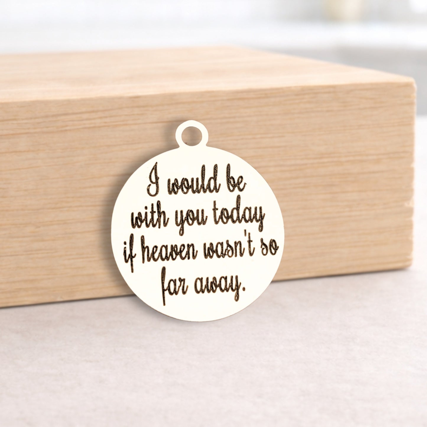 Round metal pendant with engraved text on a wooden block