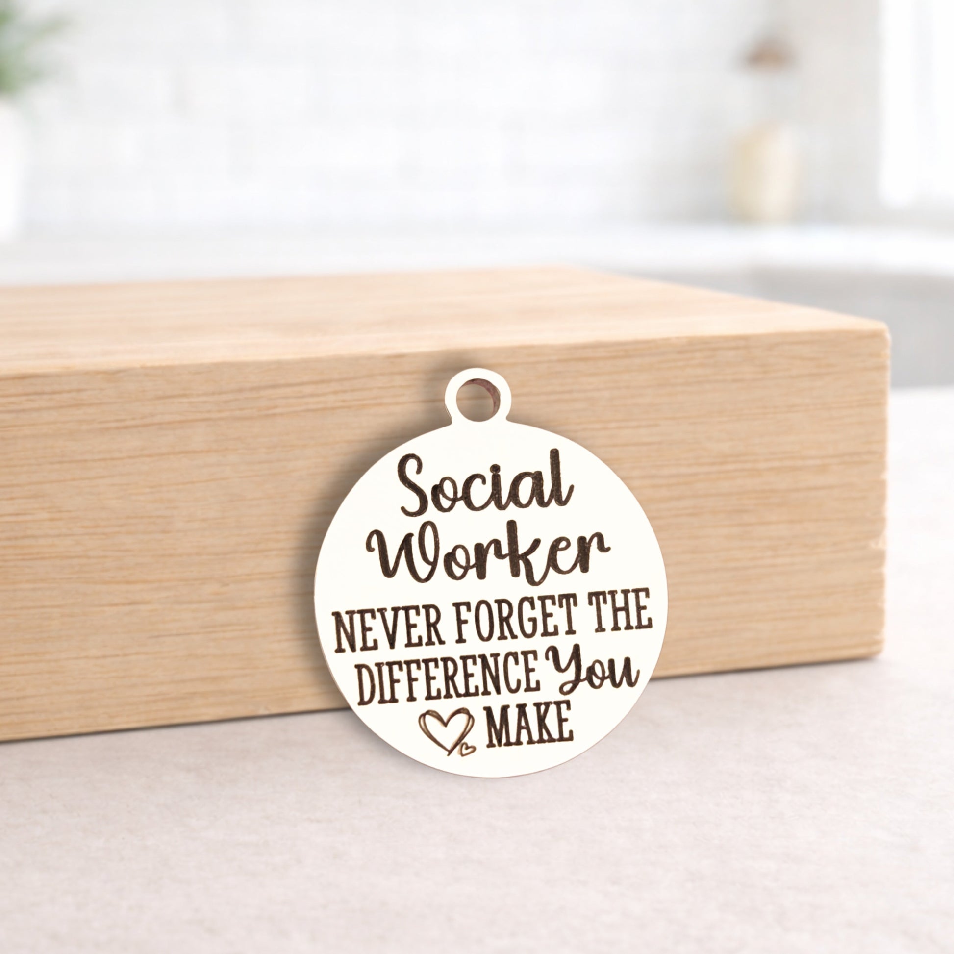 Round pendant with 'Social Worker Never Forget The Difference You Make' text on a wooden block.