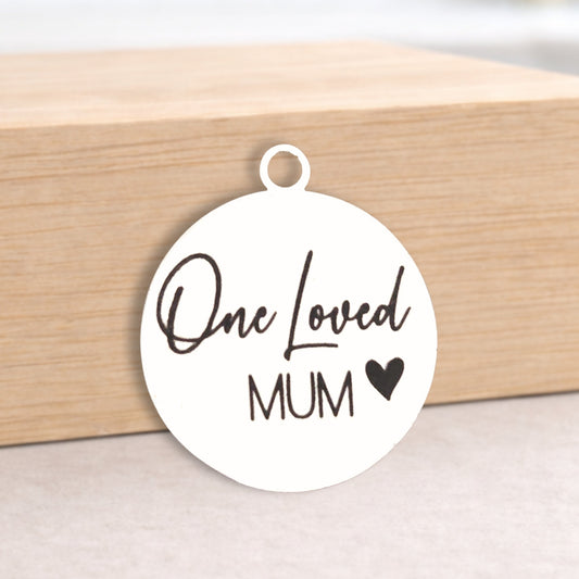Round white pendant with 'One Loved Mum' text on a wooden block