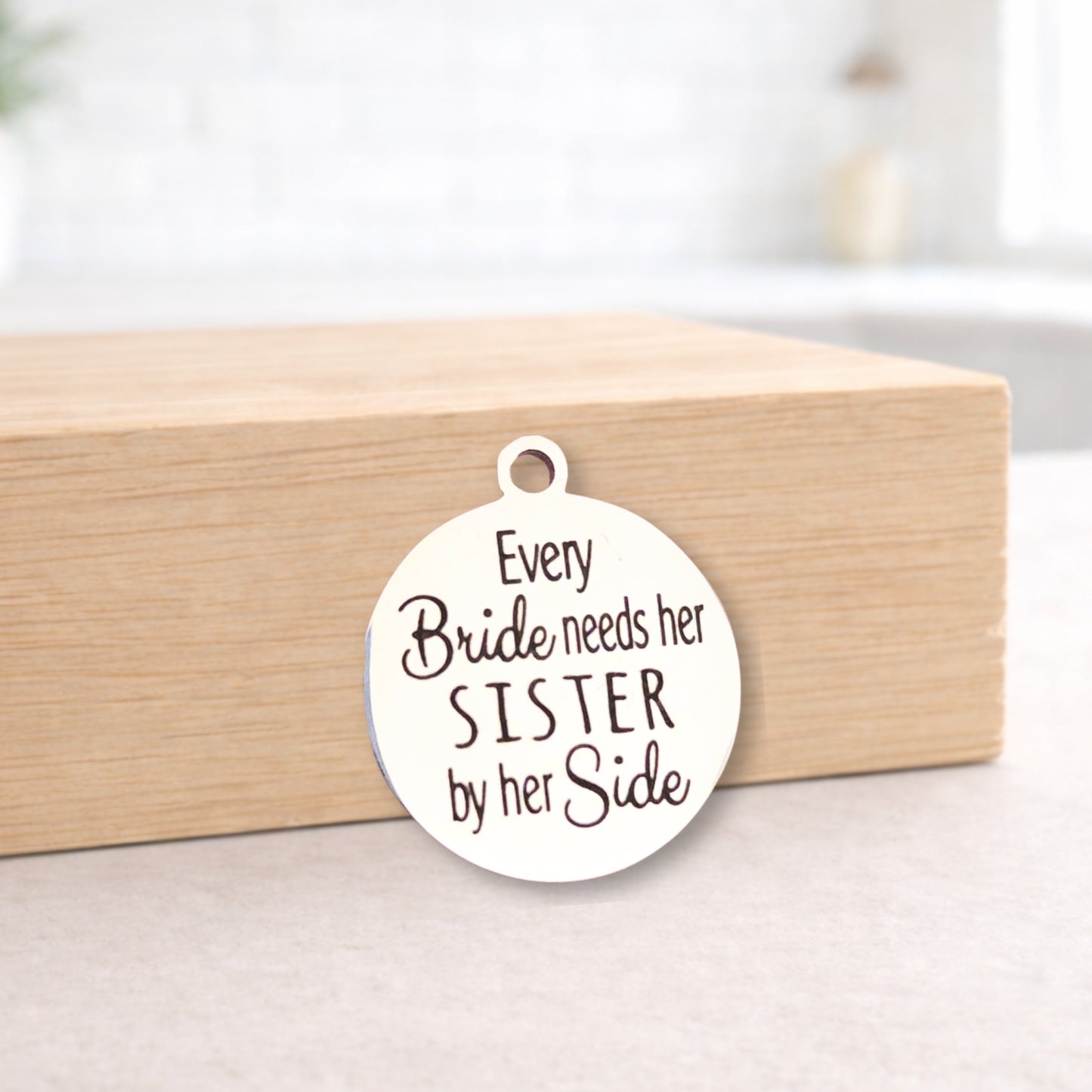 Round white pendant with engraved text on a wooden block