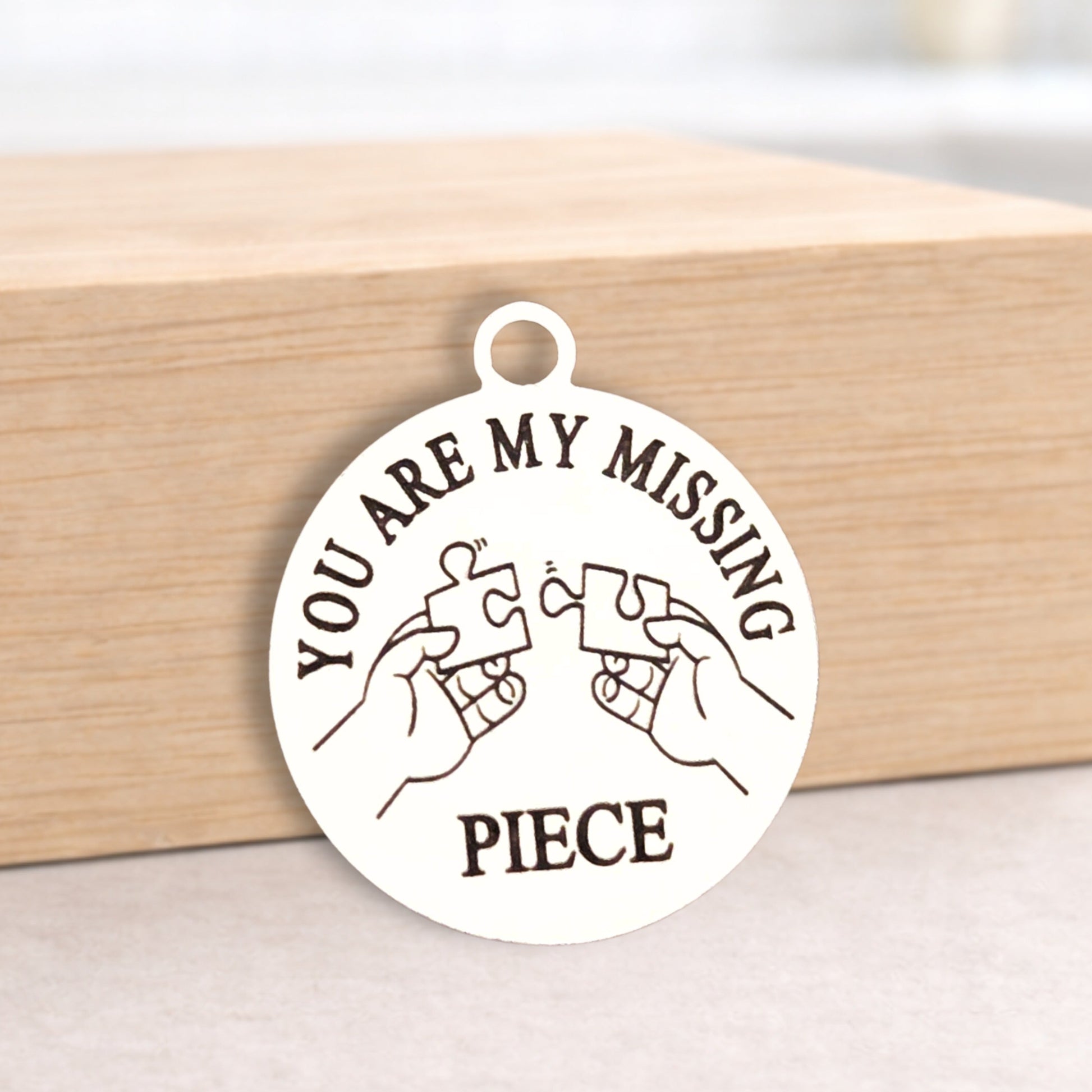 Round pendant with 'You are my missing piece' text on a wooden block